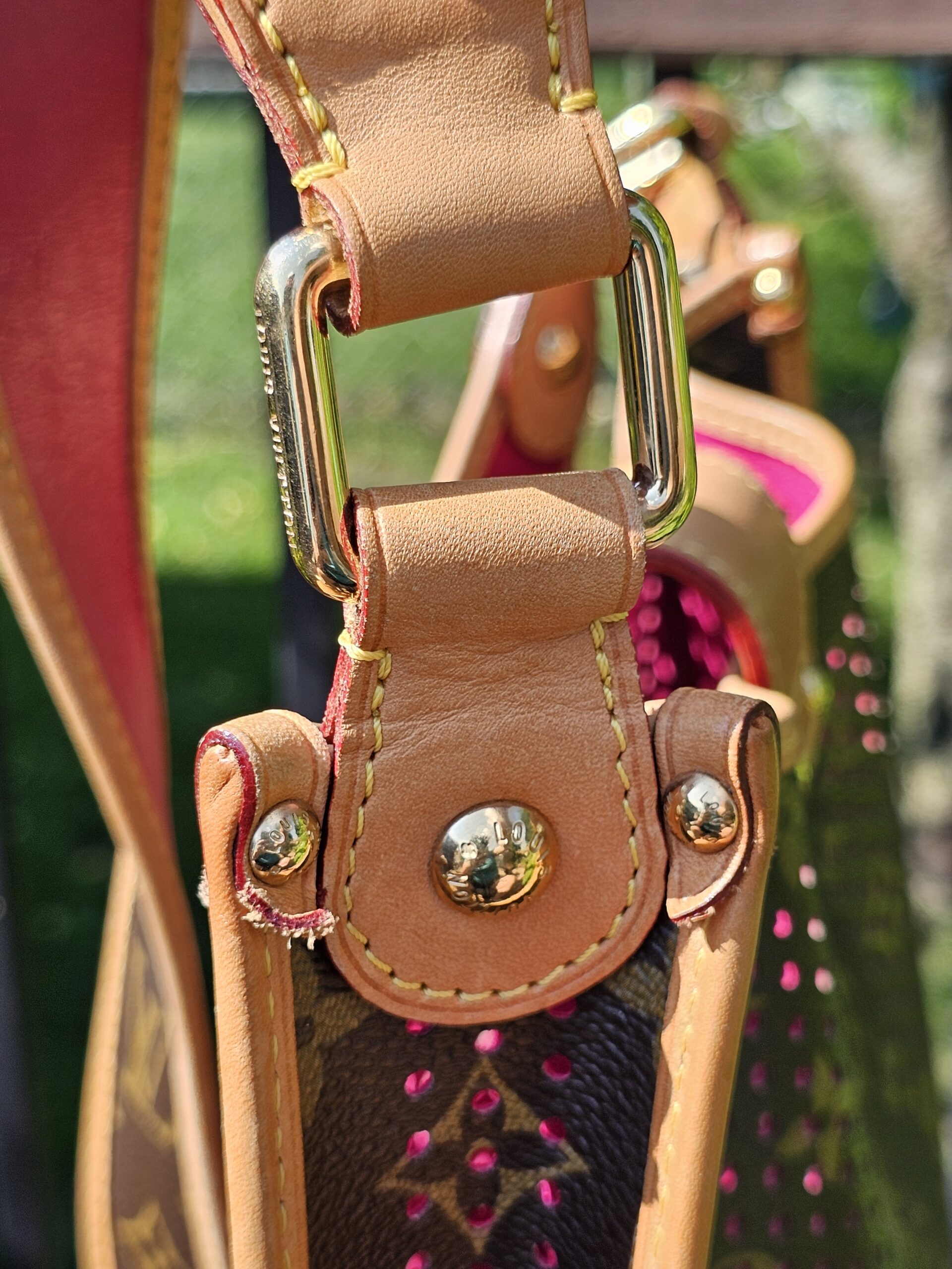 Close-up of the upper side hardware on the Louis Vuitton Monogram Perforated Musette showing wear and fraying to the leather tab