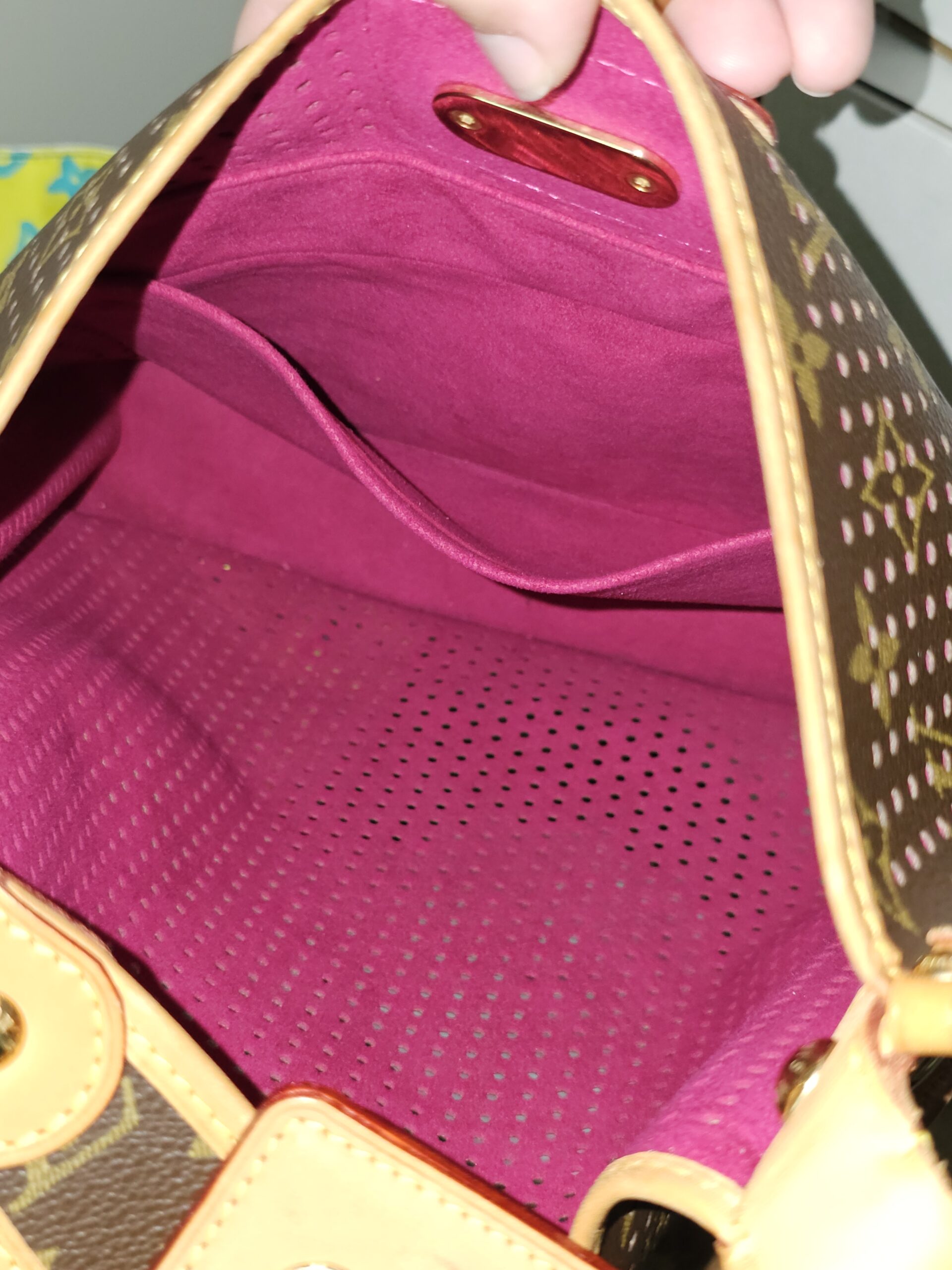Interior of the Louis Vuitton Monogram Perforated Musette showing the fuchsia lining and slip pocket