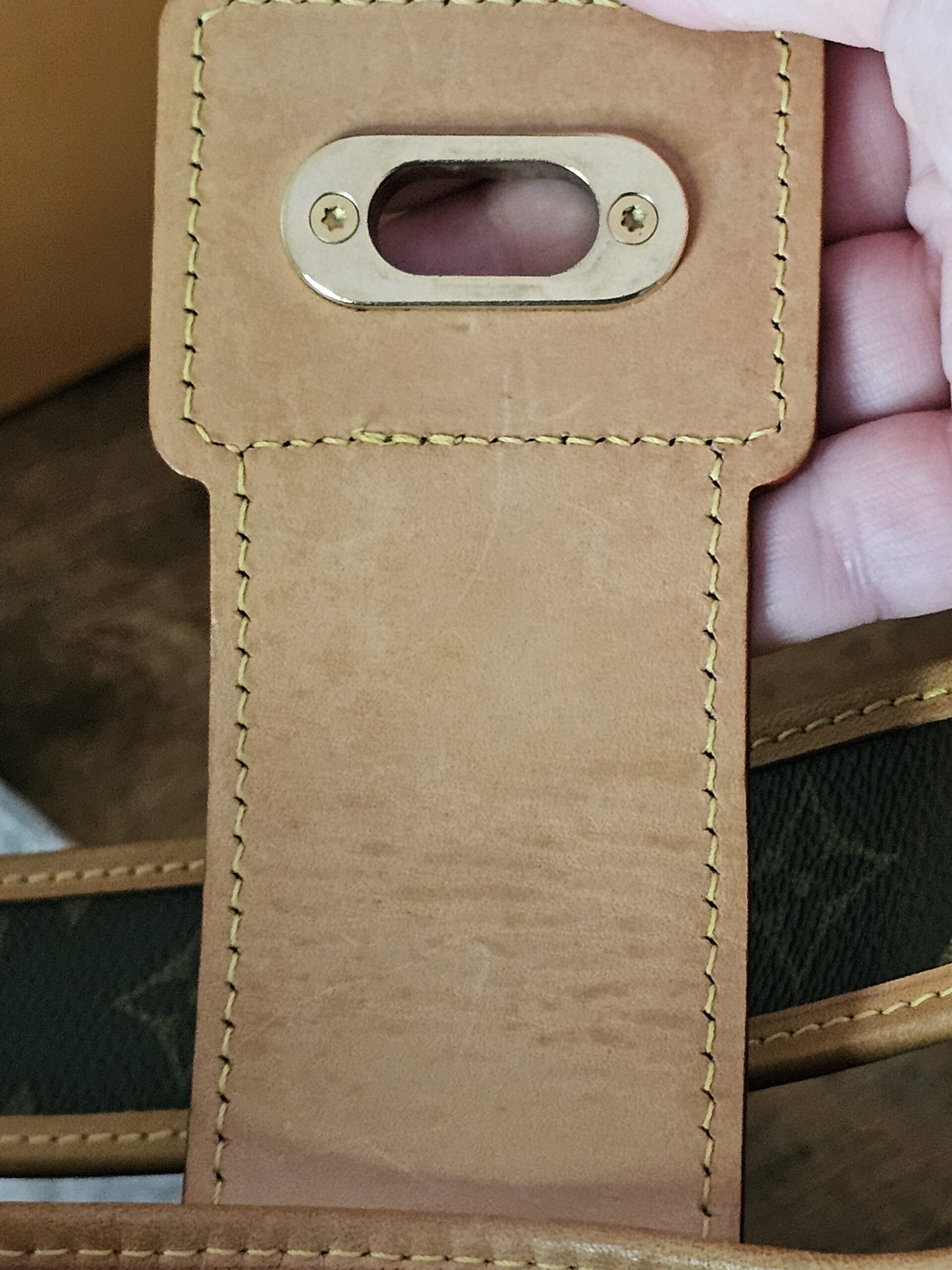 Underside of the vachetta flap on the Louis Vuitton Monogram Perforated Musette showing the lock plate