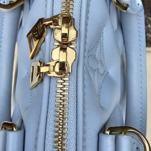 Gold-tone D-ring and zip pulls on the side of the Louis Vuitton Bubblegram Alma BB