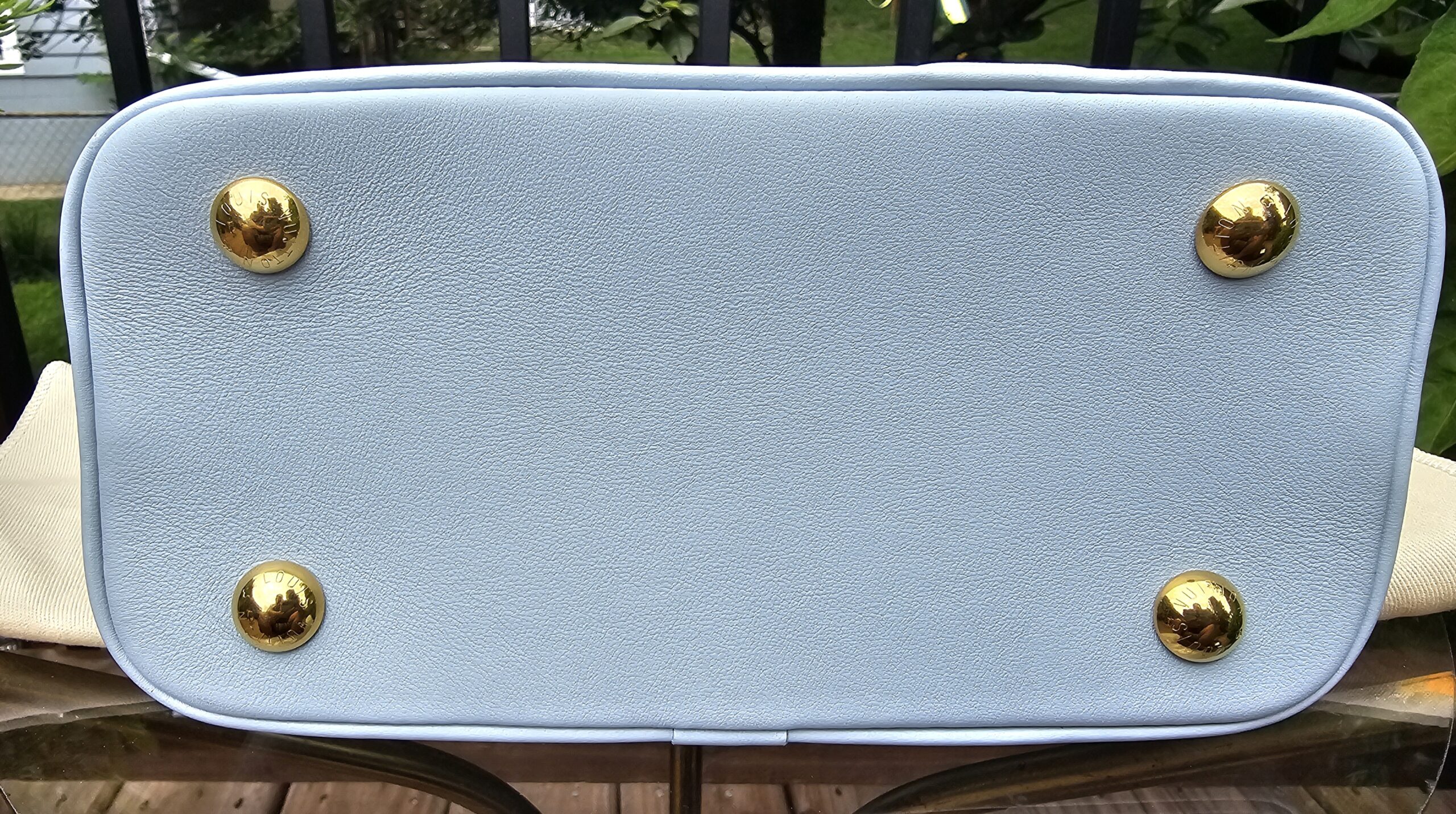 Base of the Louis Vuitton Bubblegram Alma BB showing the four protective gold metal feet