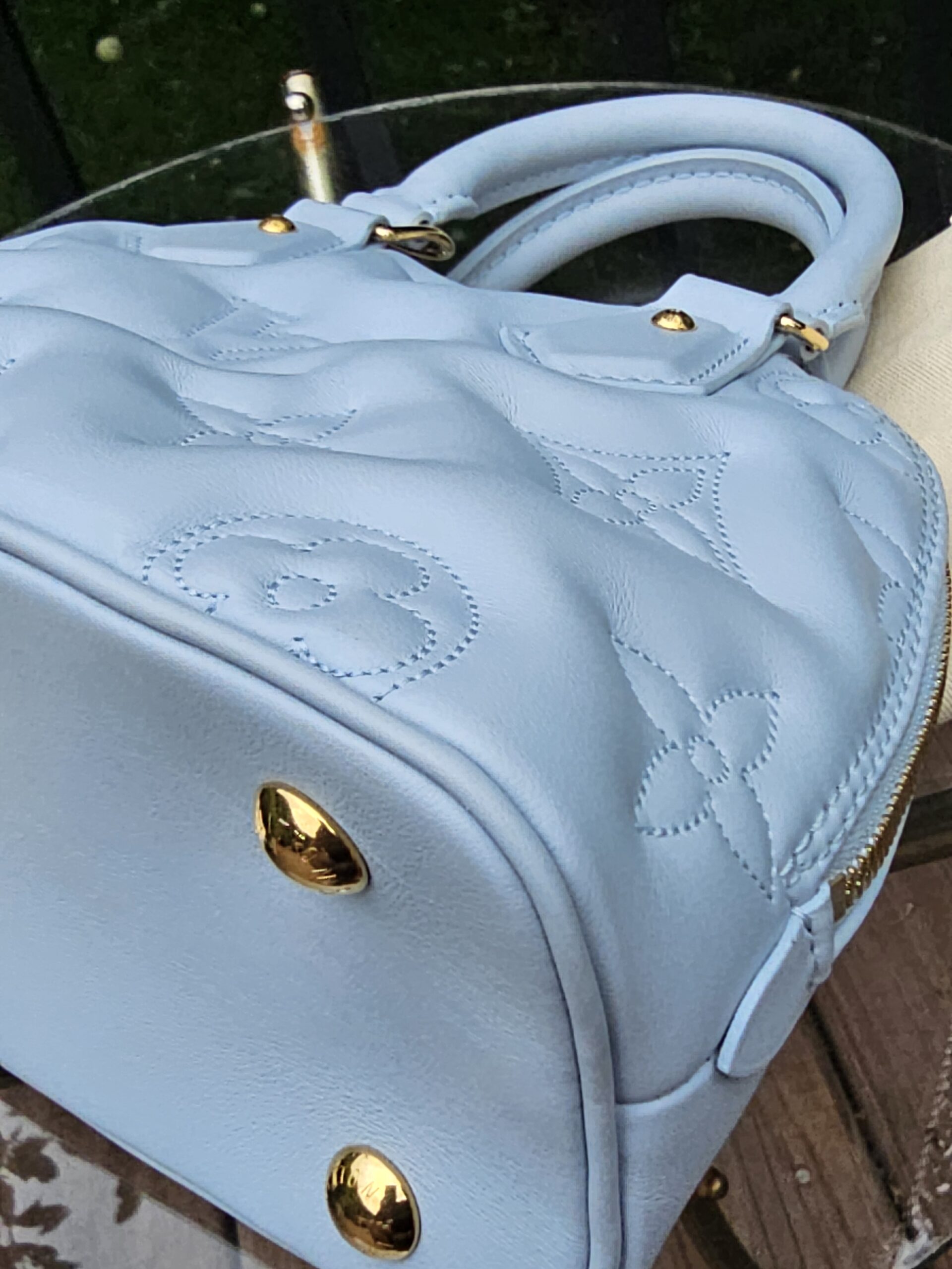 Rolled leather top handles of the Louis Vuitton Bubblegram Alma BB in Ice Blue