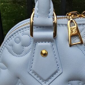 Gold-tone handle attachment hardware on the Louis Vuitton Bubblegram Alma BB