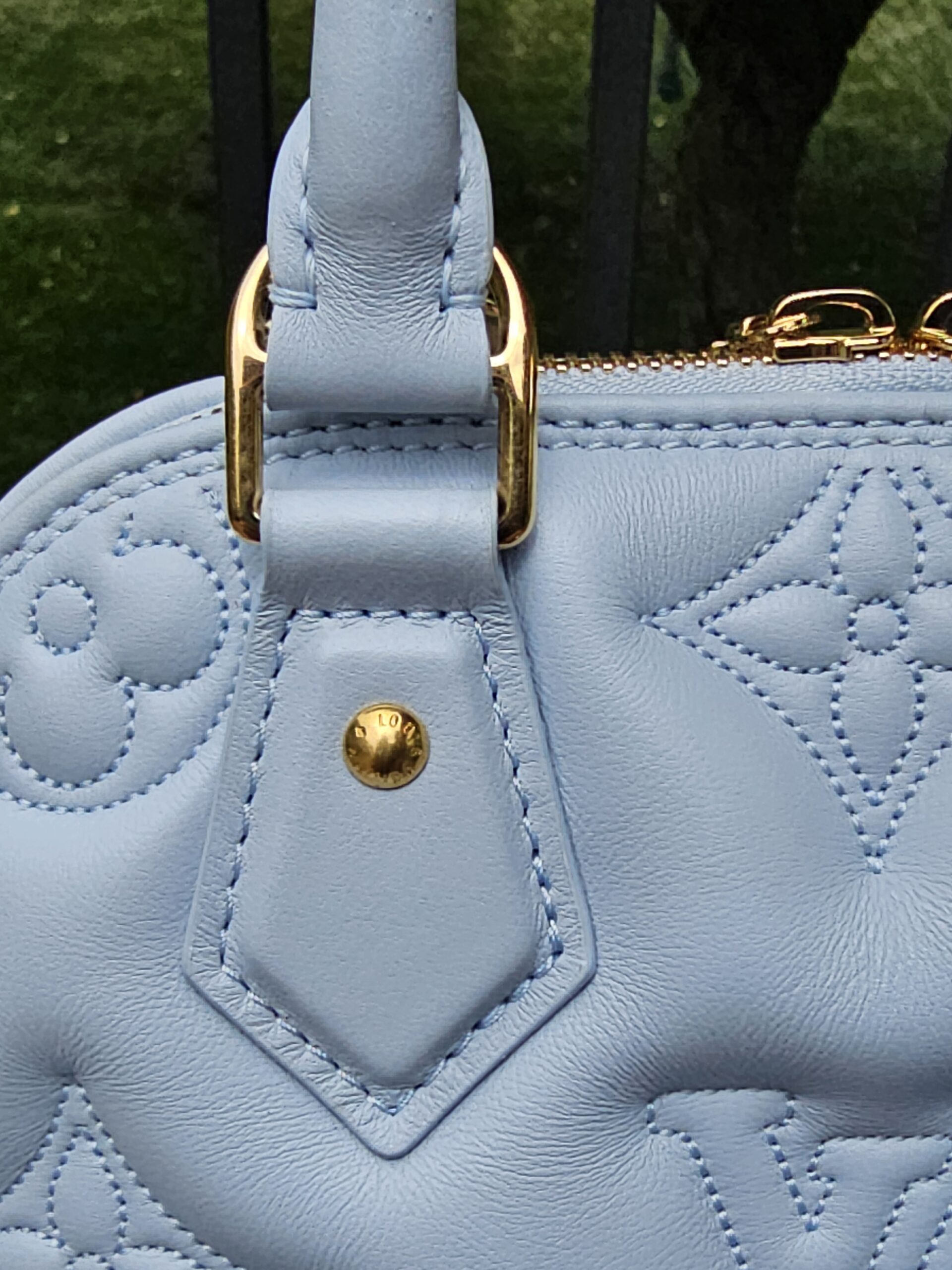 Top handles and gold hardware of the Louis Vuitton Bubblegram Alma BB in Ice Blue