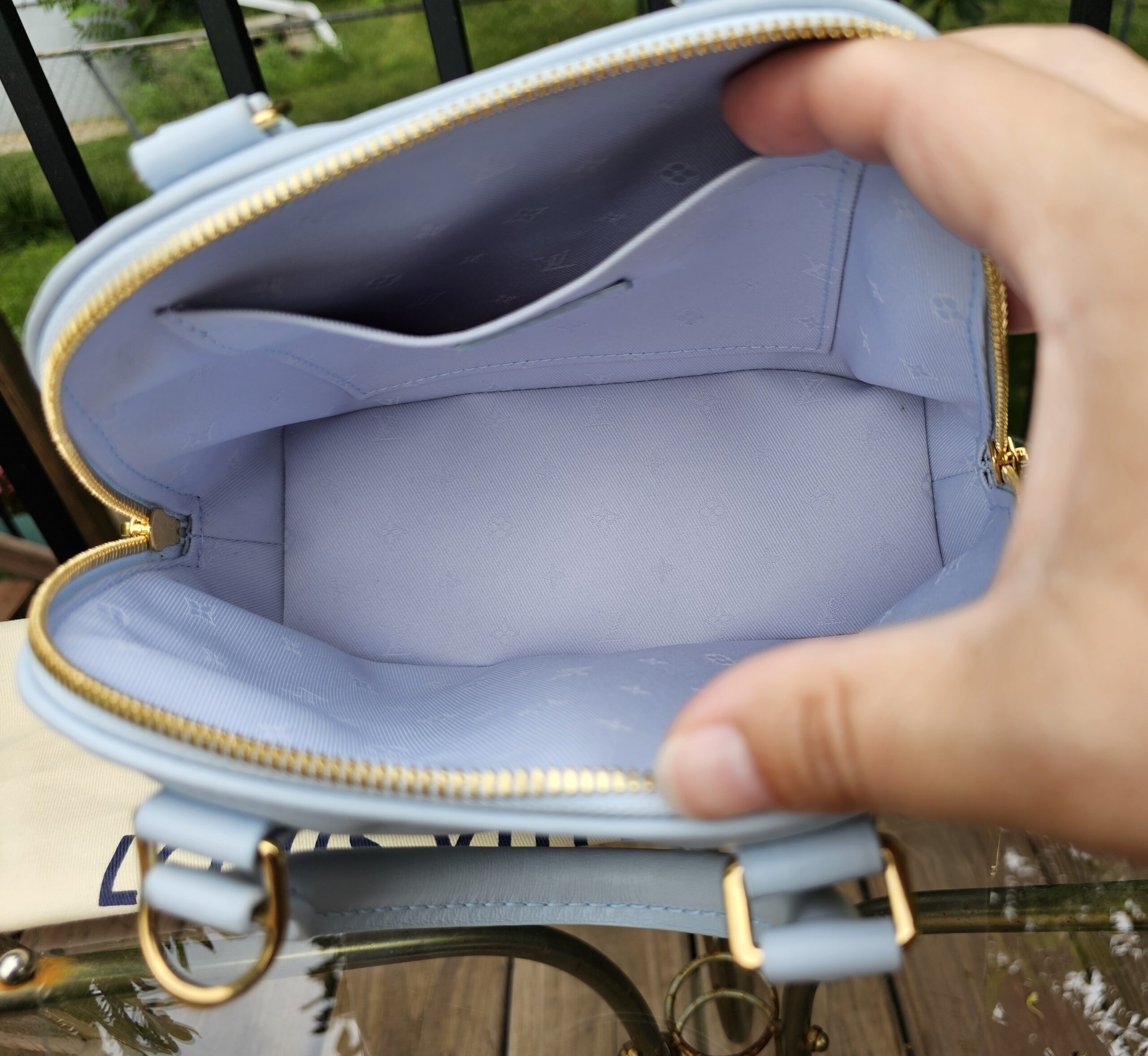 Louis Vuitton Bubblegram Alma BB held open showing the clean Monogram textile interior