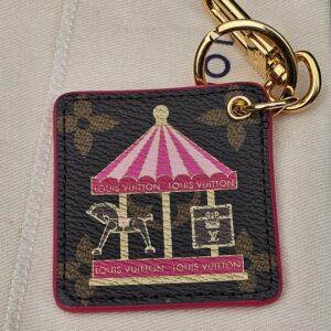 Pink carousel illustration with metallic gold accents on the Monogram canvas face of the Louis Vuitton Illustre charm