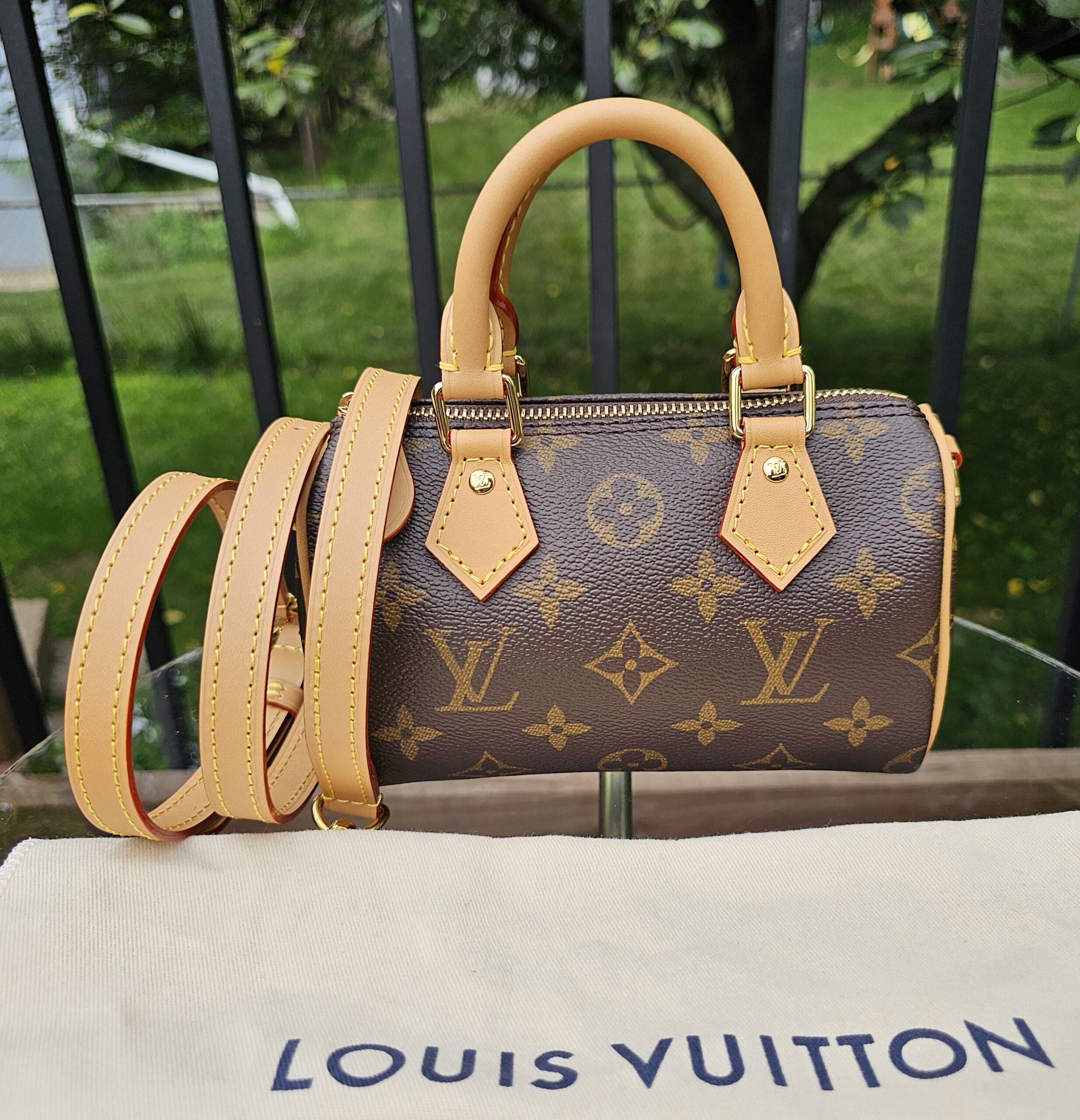 Louis Vuitton Nano Speedy Bandouliere in Monogram canvas shown with its removable vachetta strap and Louis Vuitton dust bag