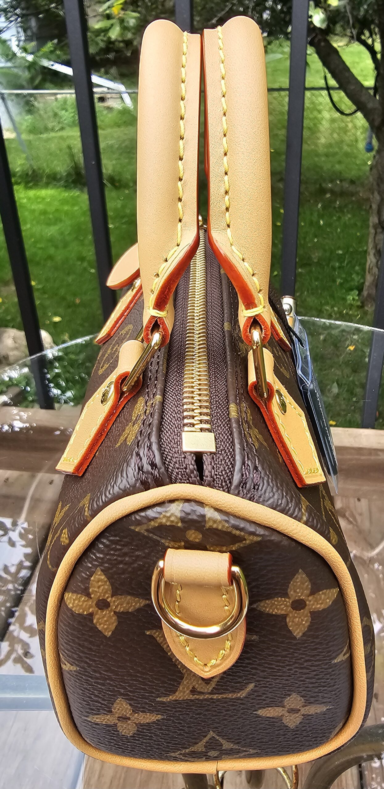 Side profile of the Louis Vuitton Nano Speedy Bandouliere showing the zip closure, piping and gold-tone D-ring