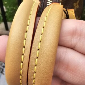 Rolled natural vachetta leather handles of the Louis Vuitton Nano Speedy Bandouliere held in hand