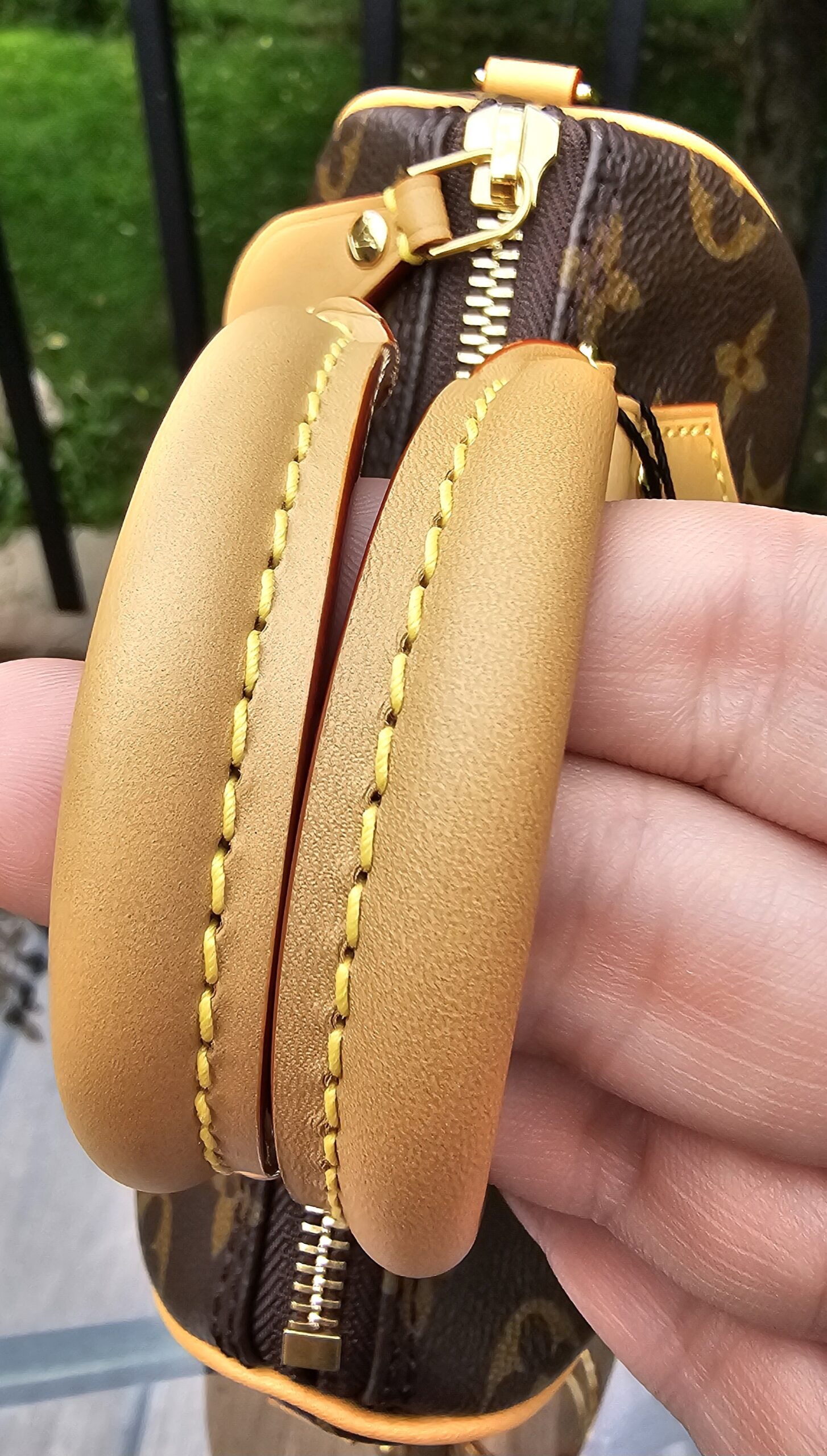 Rolled natural vachetta leather handles of the Louis Vuitton Nano Speedy Bandouliere held in hand
