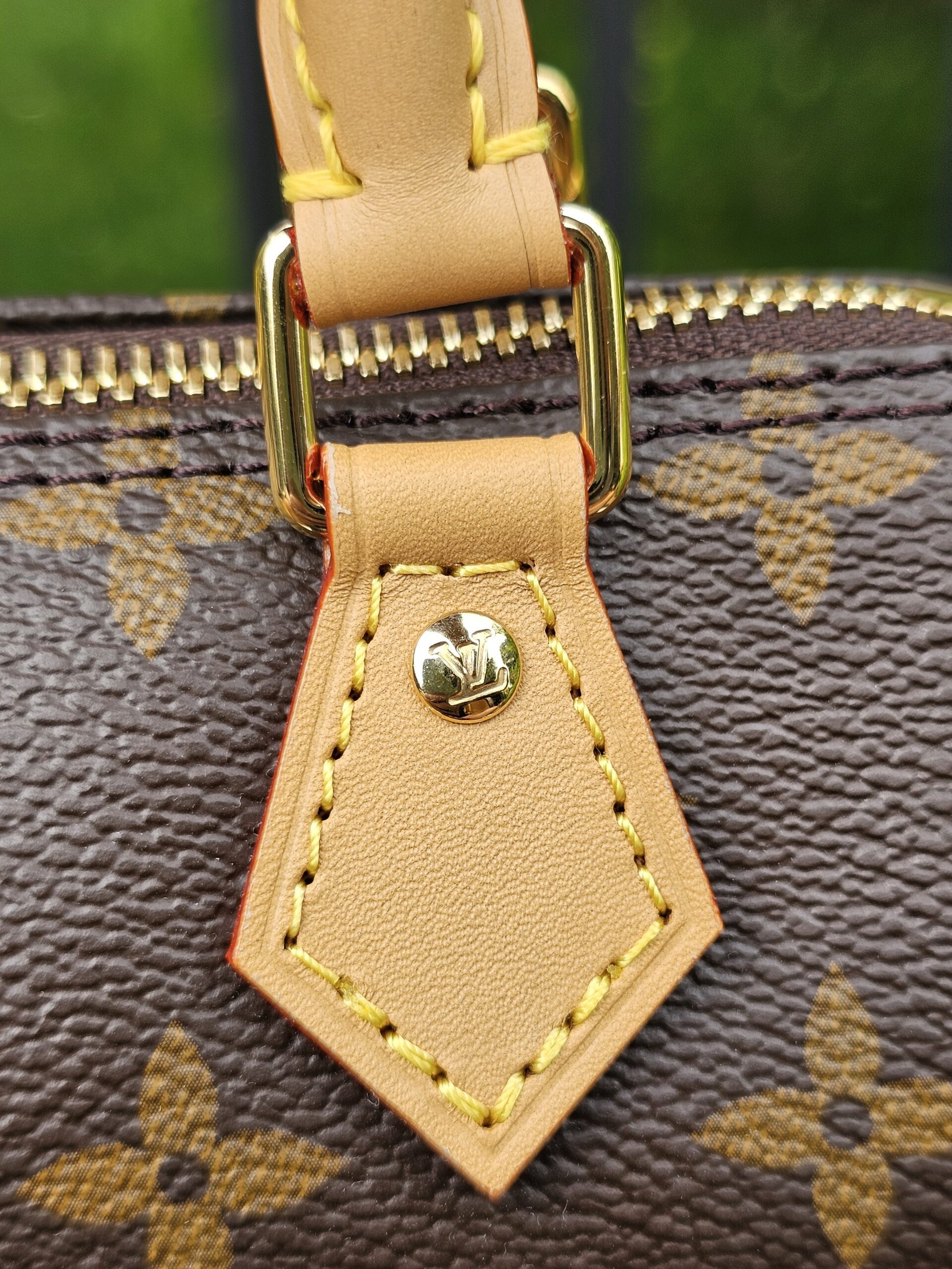 Close-up of the gold-tone zip pull and vachetta leather tab on the Louis Vuitton Nano Speedy Bandouliere