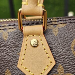 Close-up of the vachetta leather tab and gold-tone ring hardware on the side of the Louis Vuitton Nano Speedy Bandouliere