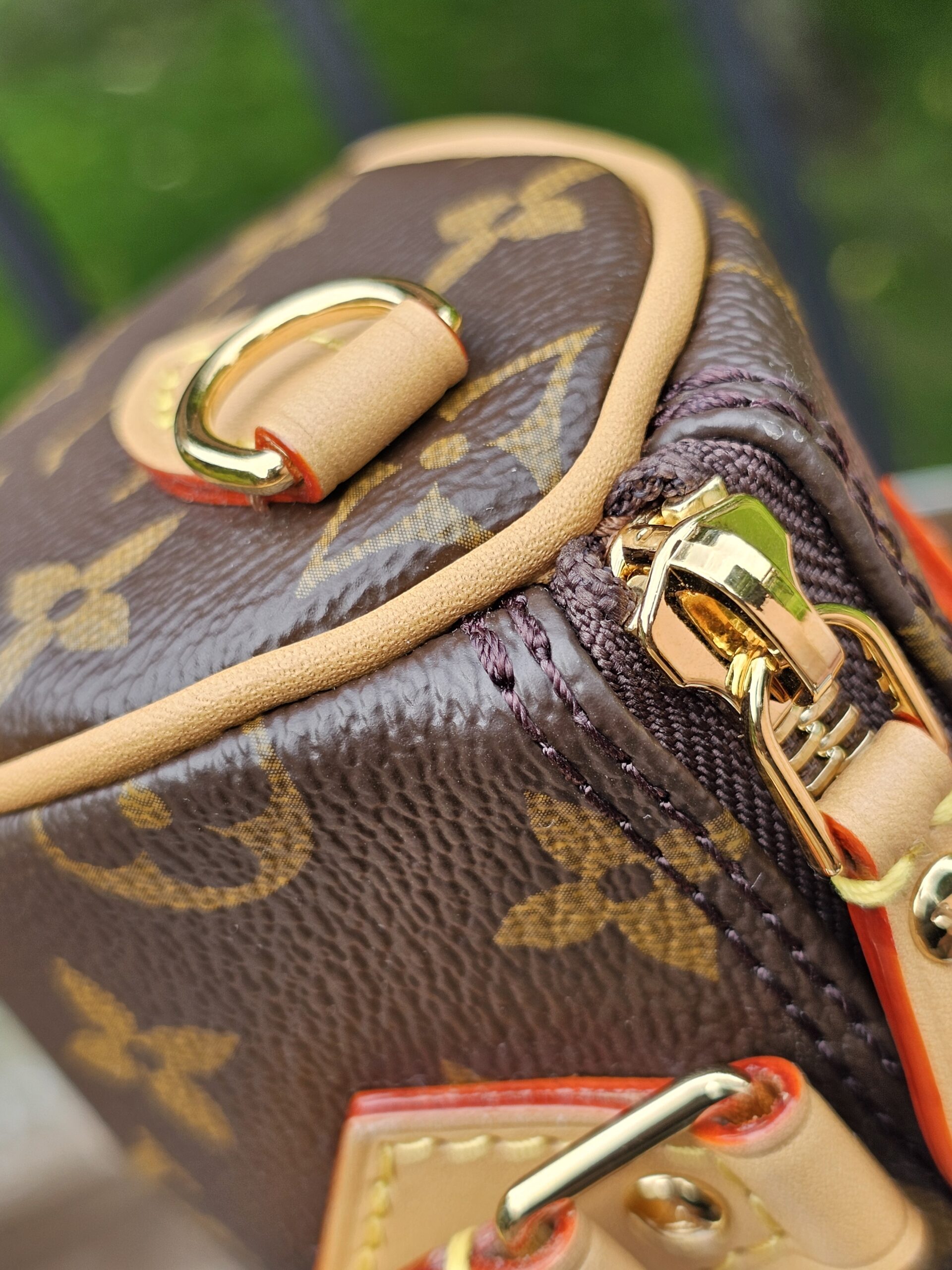 Top corner of the Louis Vuitton Nano Speedy Bandouliere showing gold-tone hardware and vachetta piping