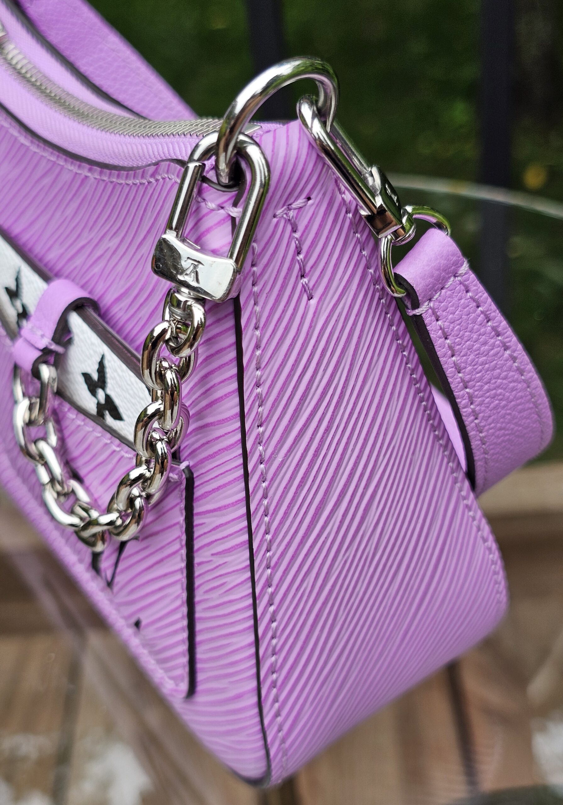 Monogram charm and silver-tone chain on the front of the Louis Vuitton Epi Marellini