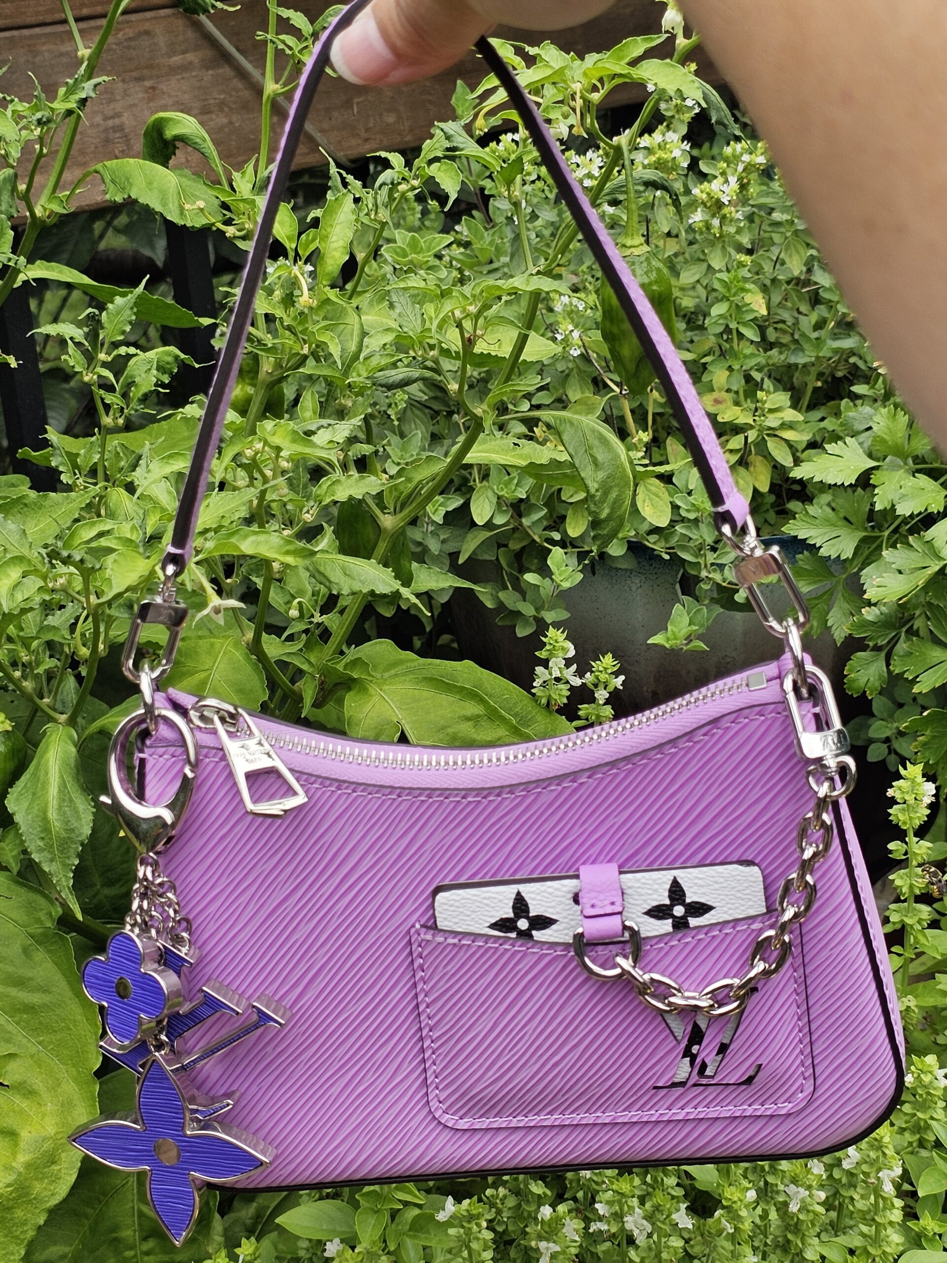 Louis Vuitton Epi Marellini in purple hanging by its chain strap outdoors