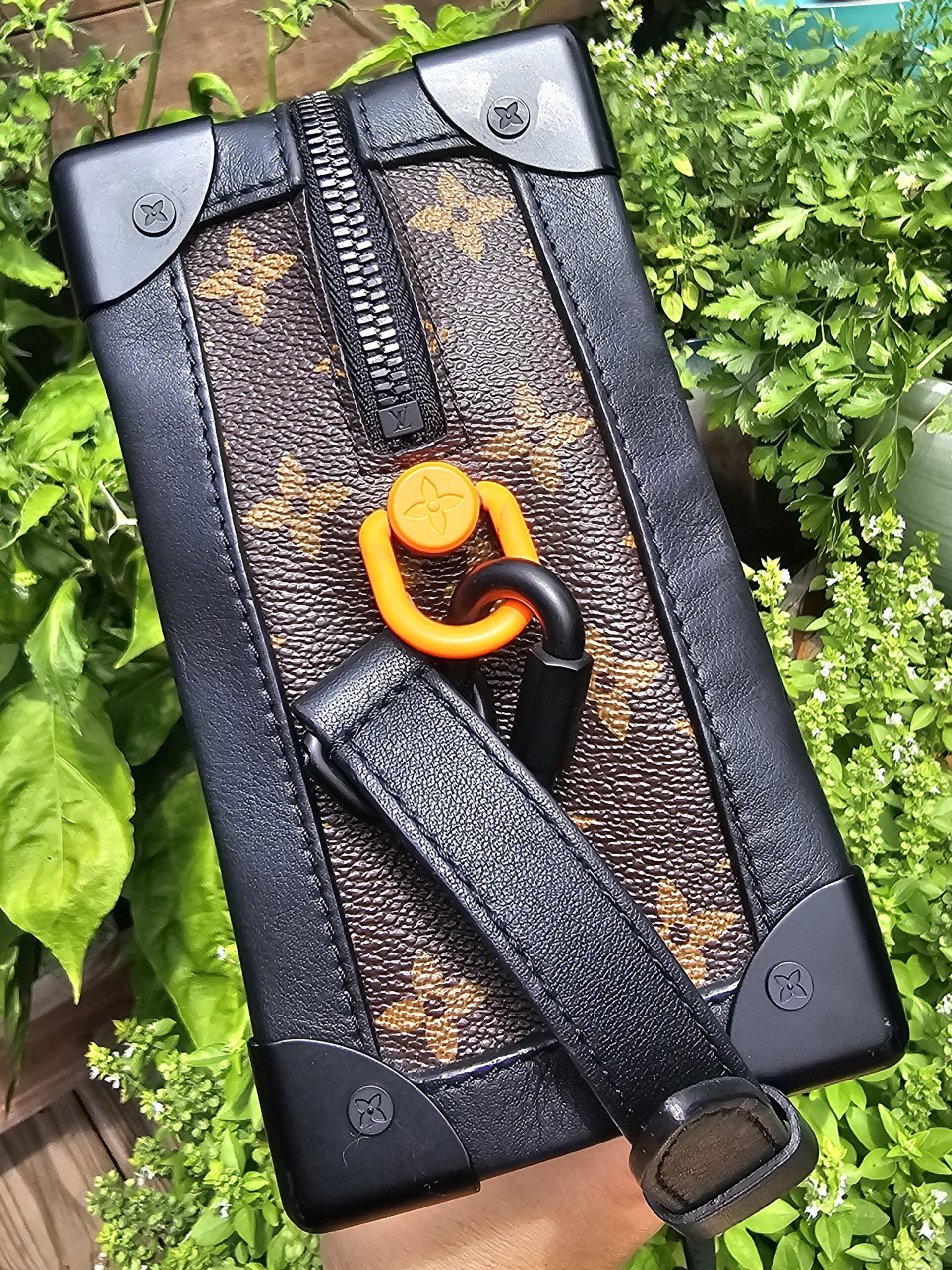 Bright orange Solar Ray carabiner and black hardware on the Louis Vuitton Soft Trunk