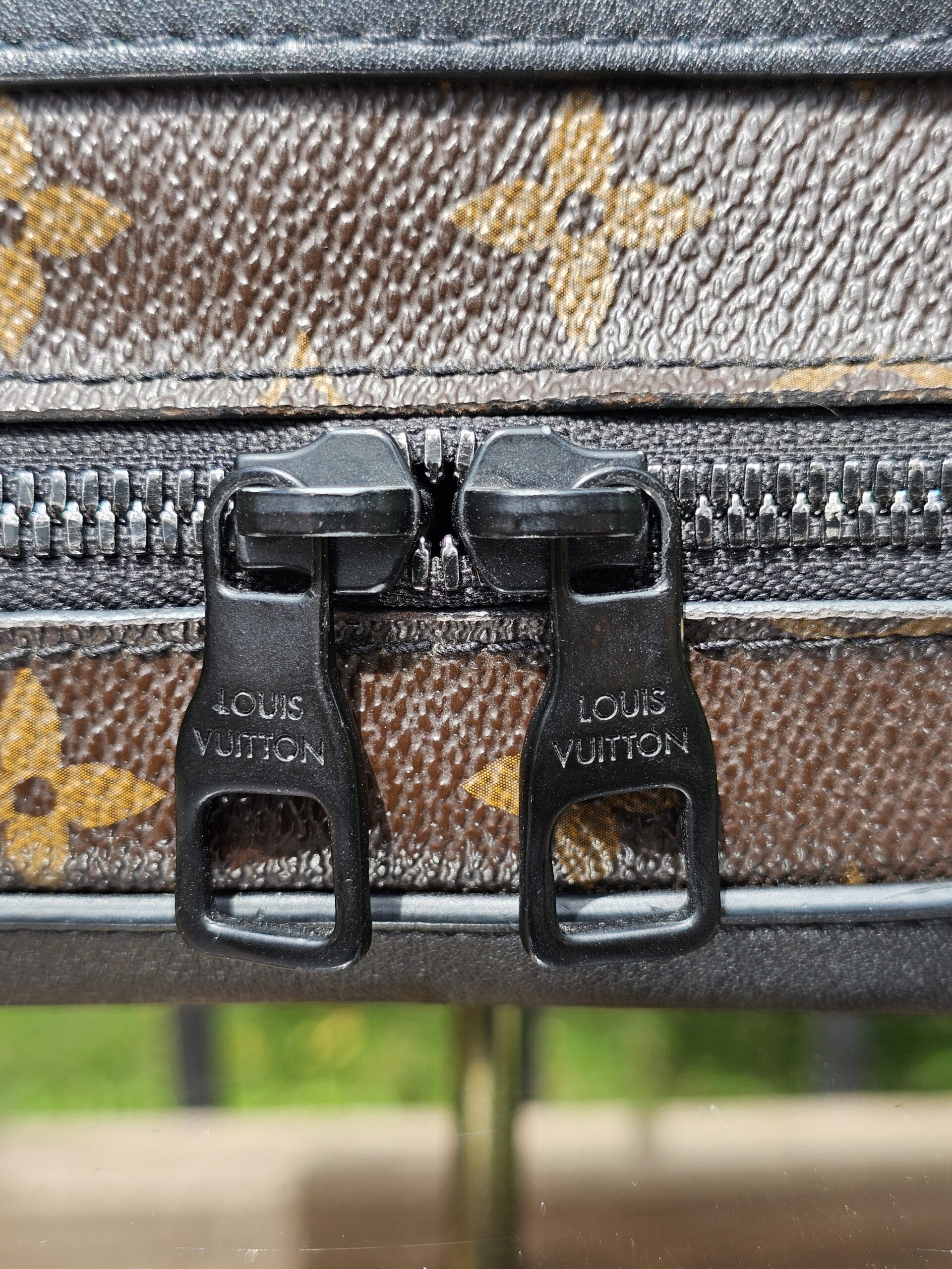 Twin black zip pulls stamped Louis Vuitton on the Monogram Solar Ray Soft Trunk