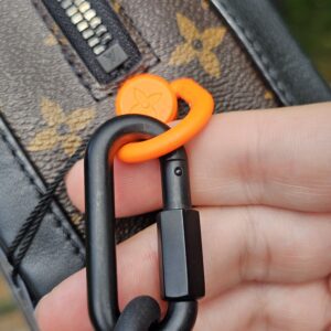 Orange Solar Ray ring and black carabiner attaching the strap to the Louis Vuitton Soft Trunk