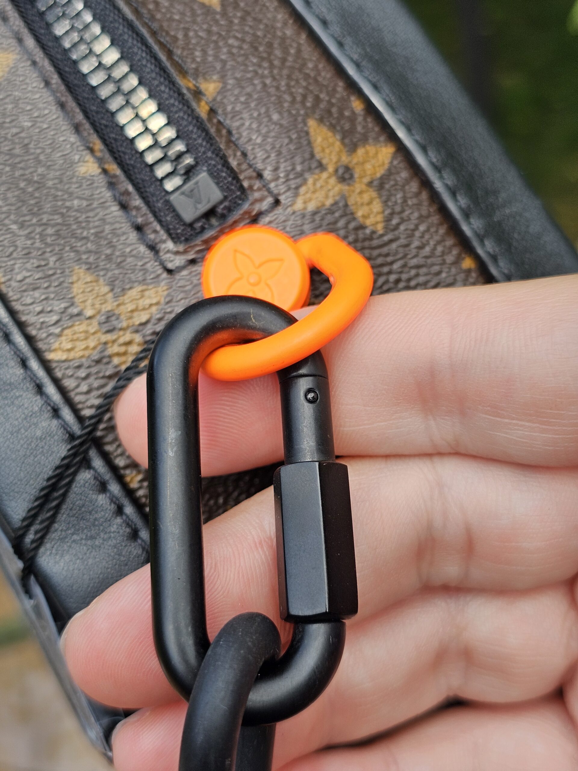 Orange Solar Ray ring and black carabiner attaching the strap to the Louis Vuitton Soft Trunk