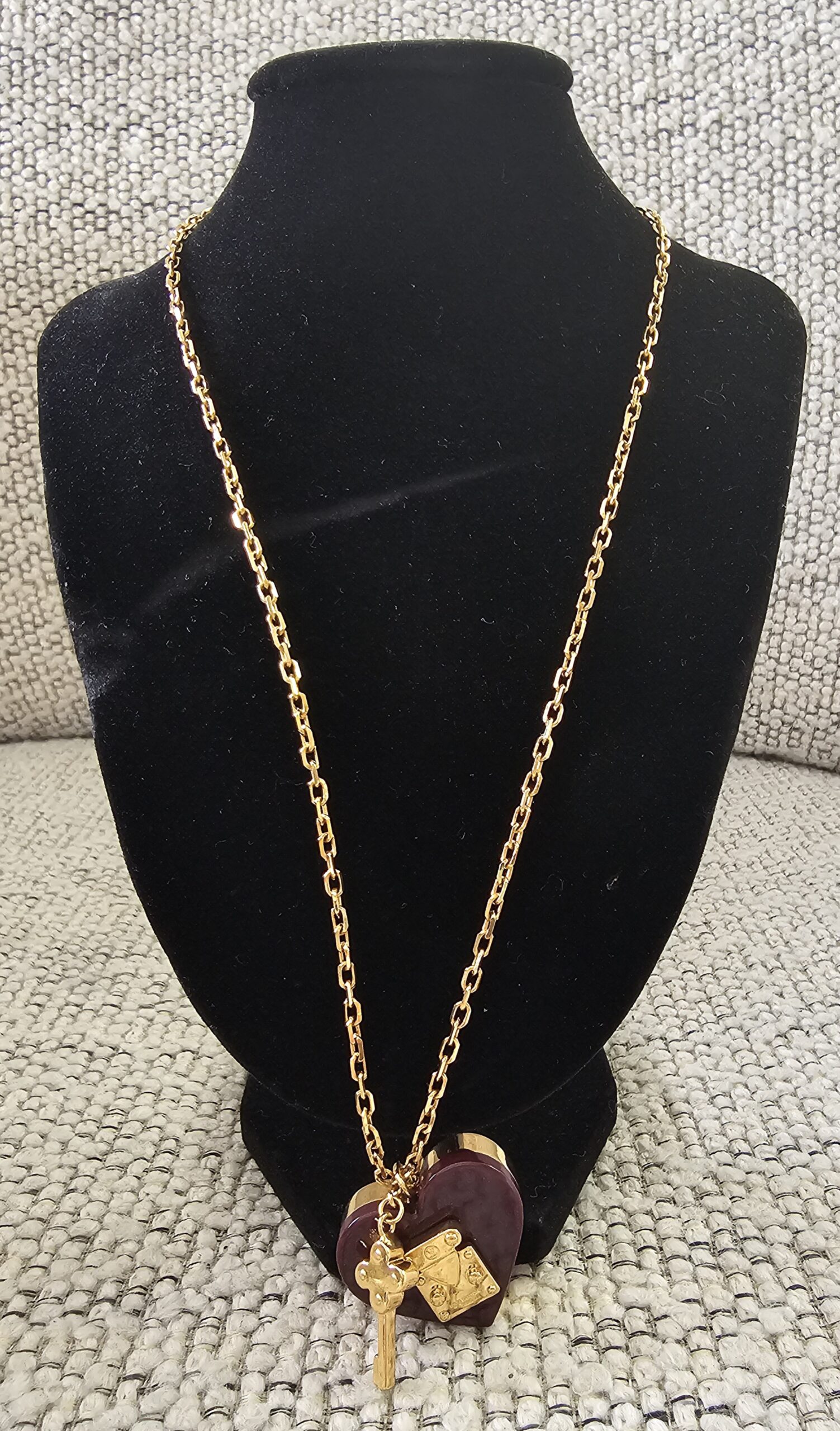 Louis Vuitton Lock Me heart necklace in burgundy resin displayed on a bust to show the chain drop