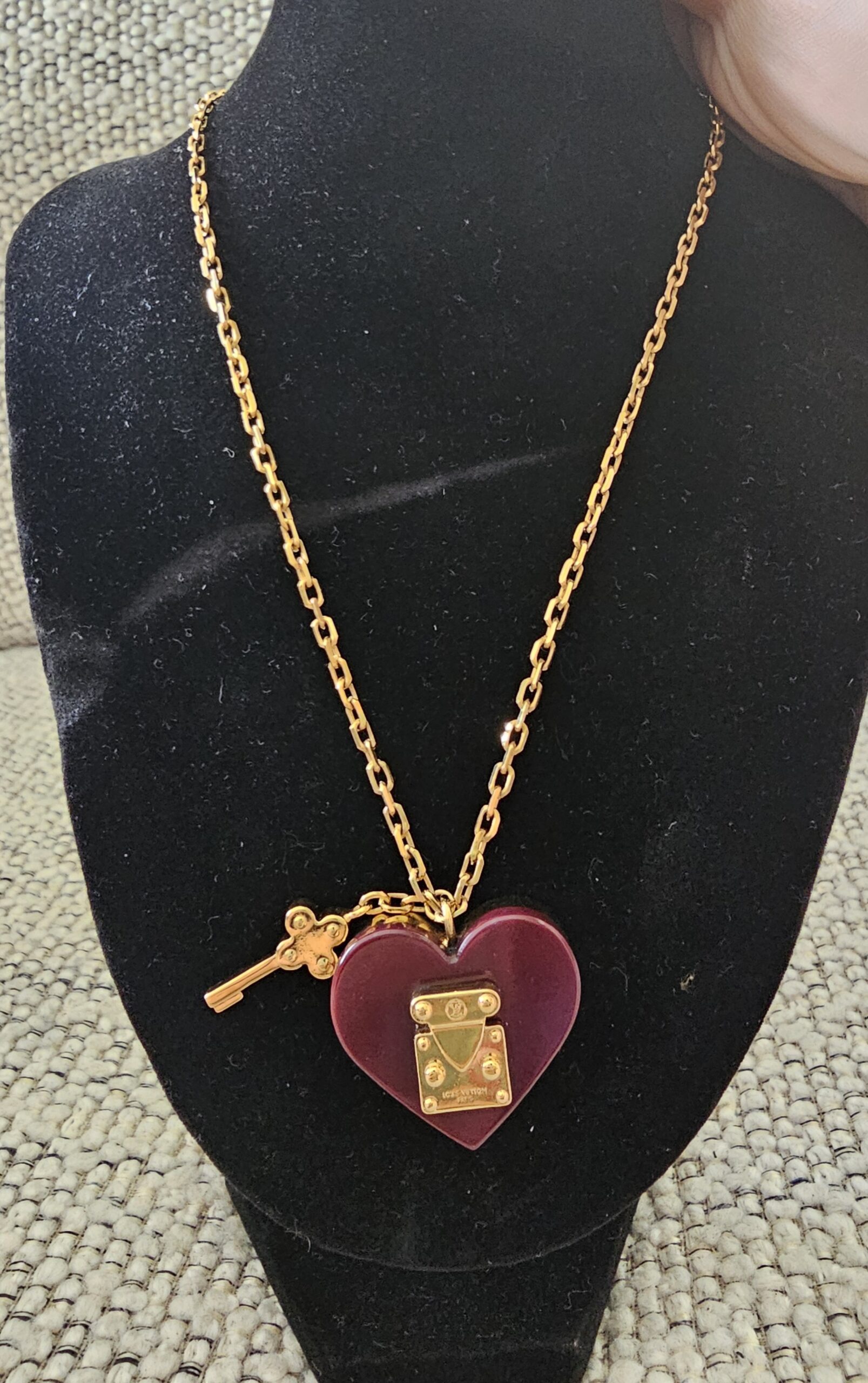 Louis Vuitton Lock Me heart necklace with burgundy resin heart, gold-tone S-lock and key charm on a gold chain