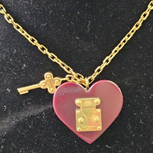 Burgundy resin heart pendant with gold-tone S-lock and dangling key charm on the Louis Vuitton necklace