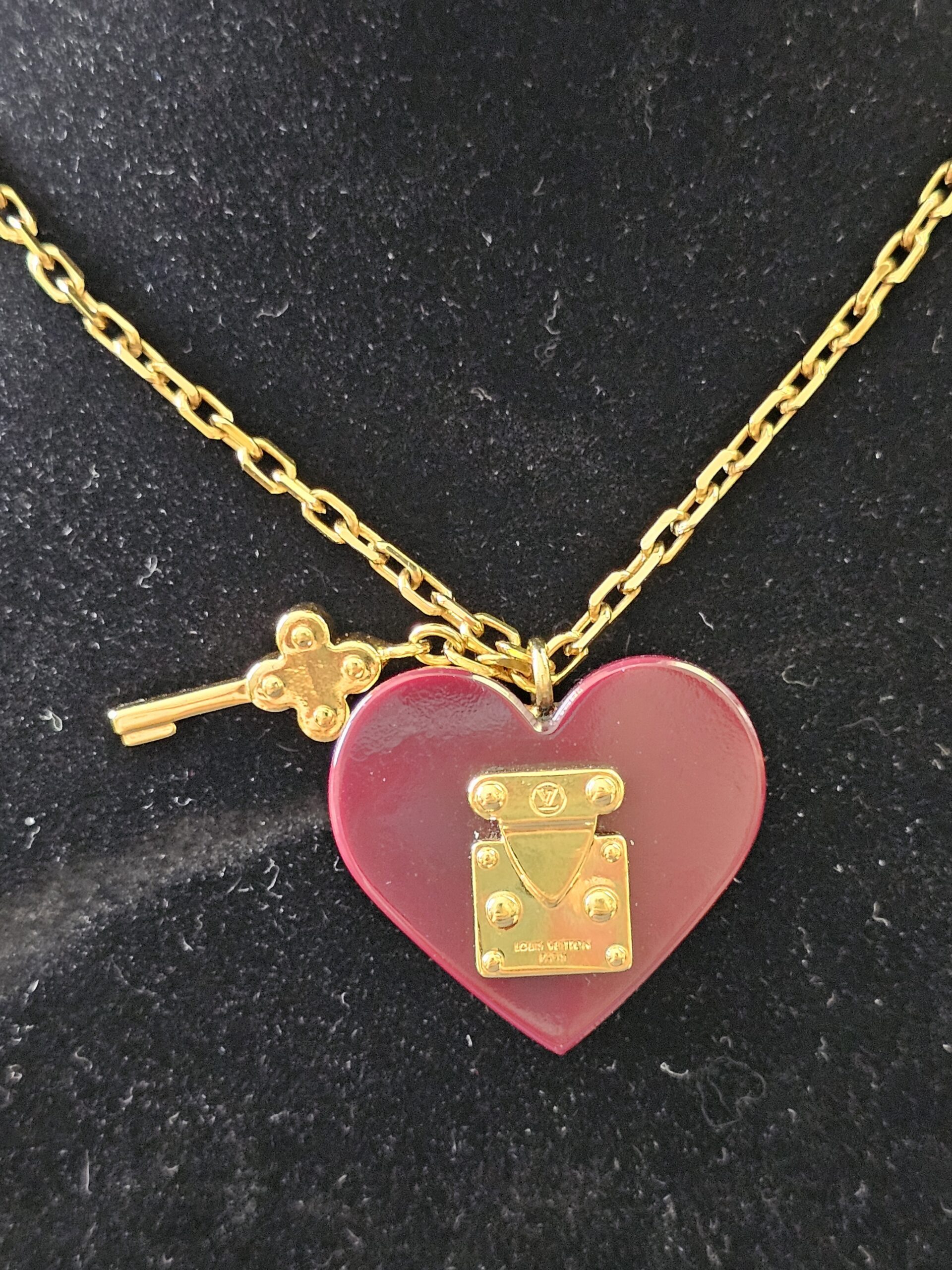Burgundy resin heart pendant with gold-tone S-lock and dangling key charm on the Louis Vuitton necklace