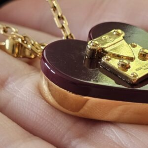Side profile of the burgundy resin heart pendant showing its depth and gold-tone edge