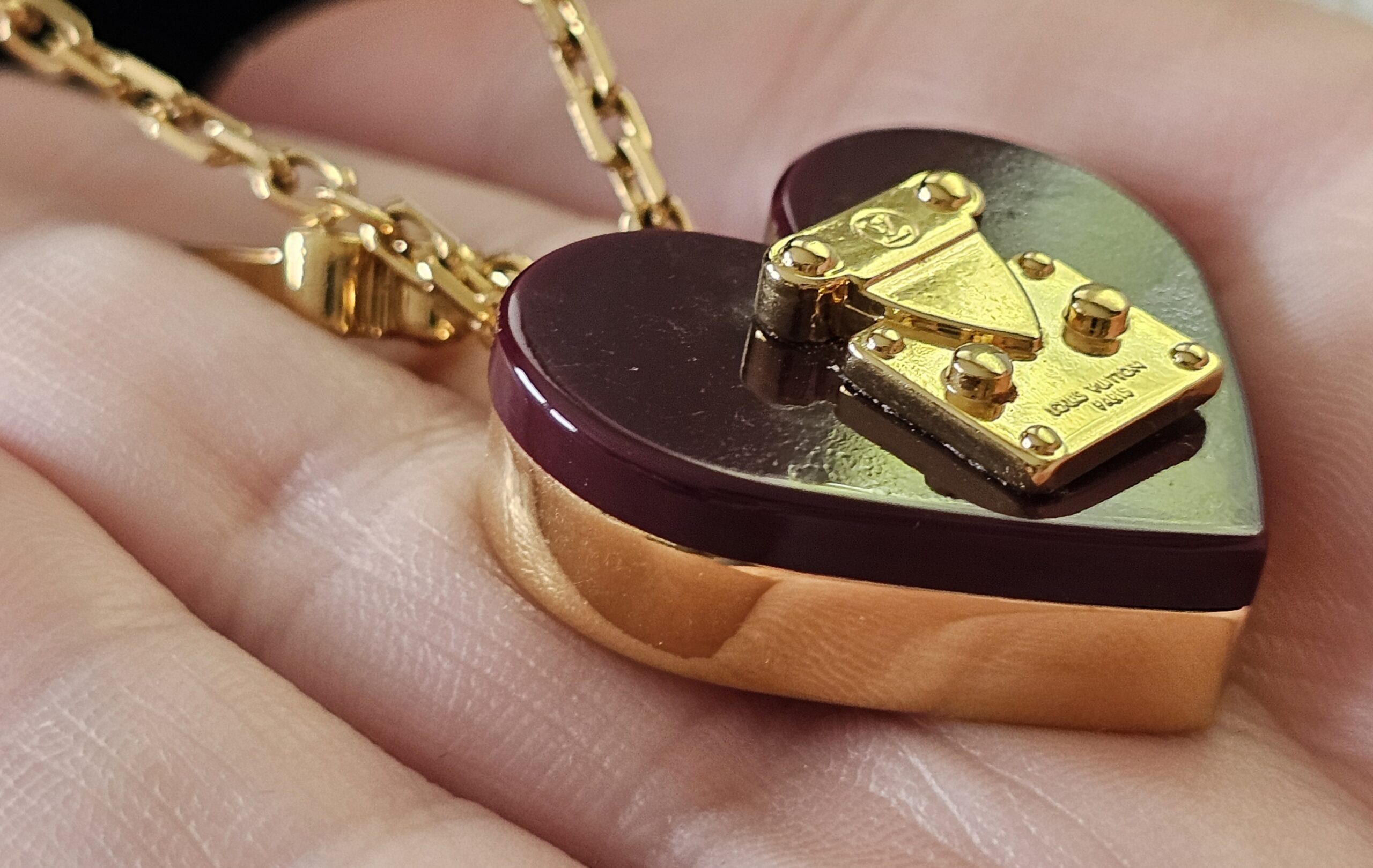 Side profile of the burgundy resin heart pendant showing its depth and gold-tone edge