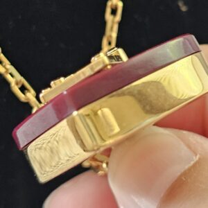 Close-up of the burgundy resin and gold-tone metal edge of the Louis Vuitton heart pendant