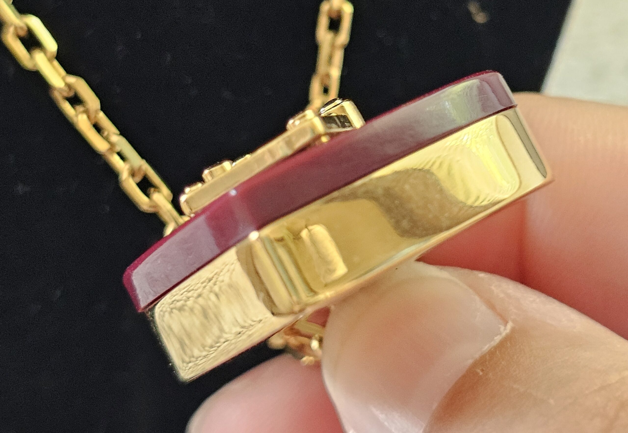 Close-up of the burgundy resin and gold-tone metal edge of the Louis Vuitton heart pendant