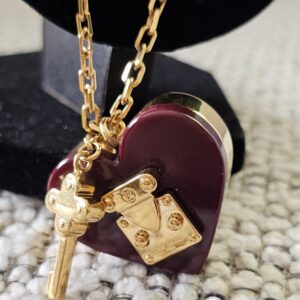 Burgundy heart pendant and gold key charm of the Louis Vuitton Lock Me necklace shown together