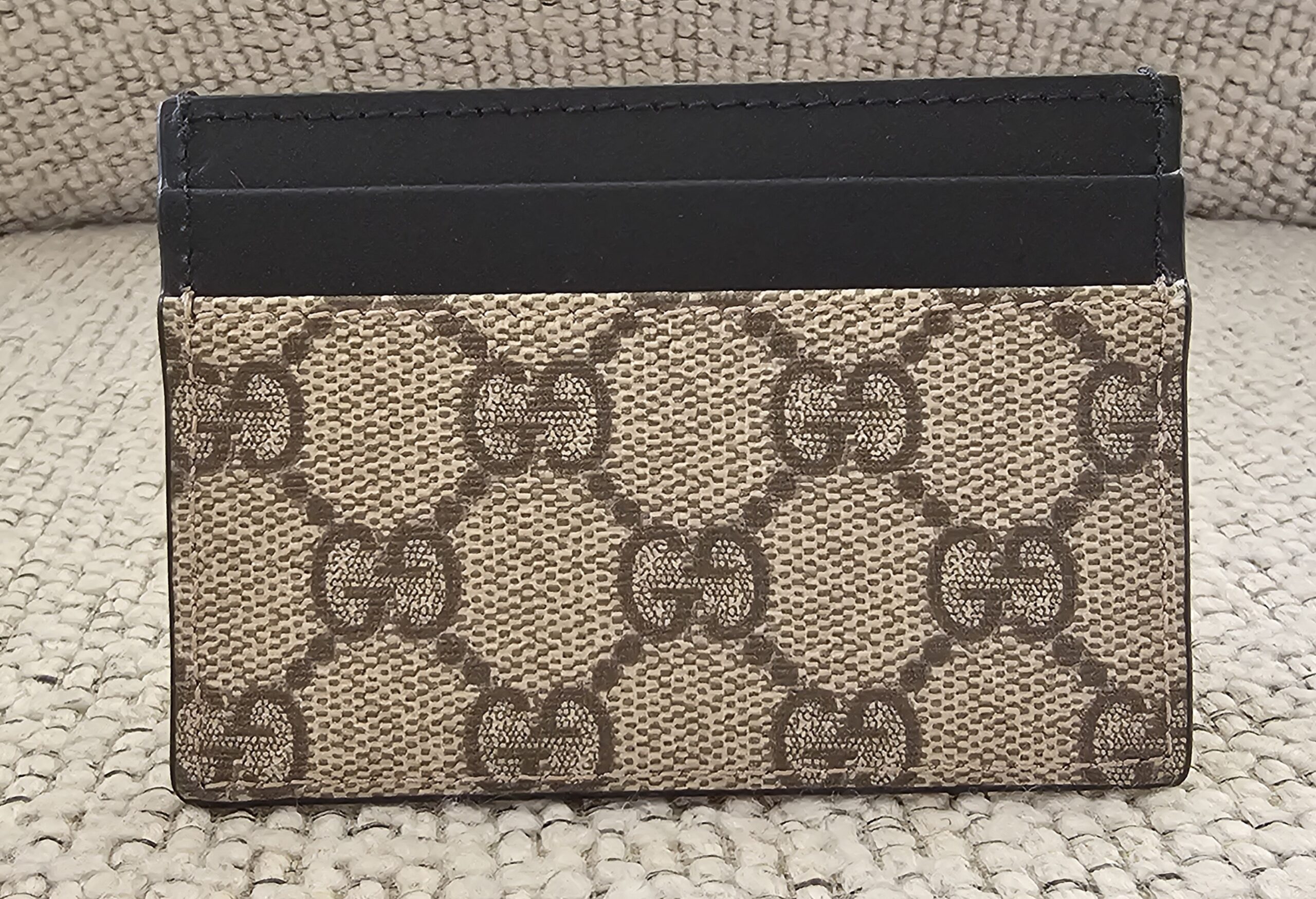 Front of the Gucci GG Supreme Essence card holder showing the GG canvas and black leather card slots