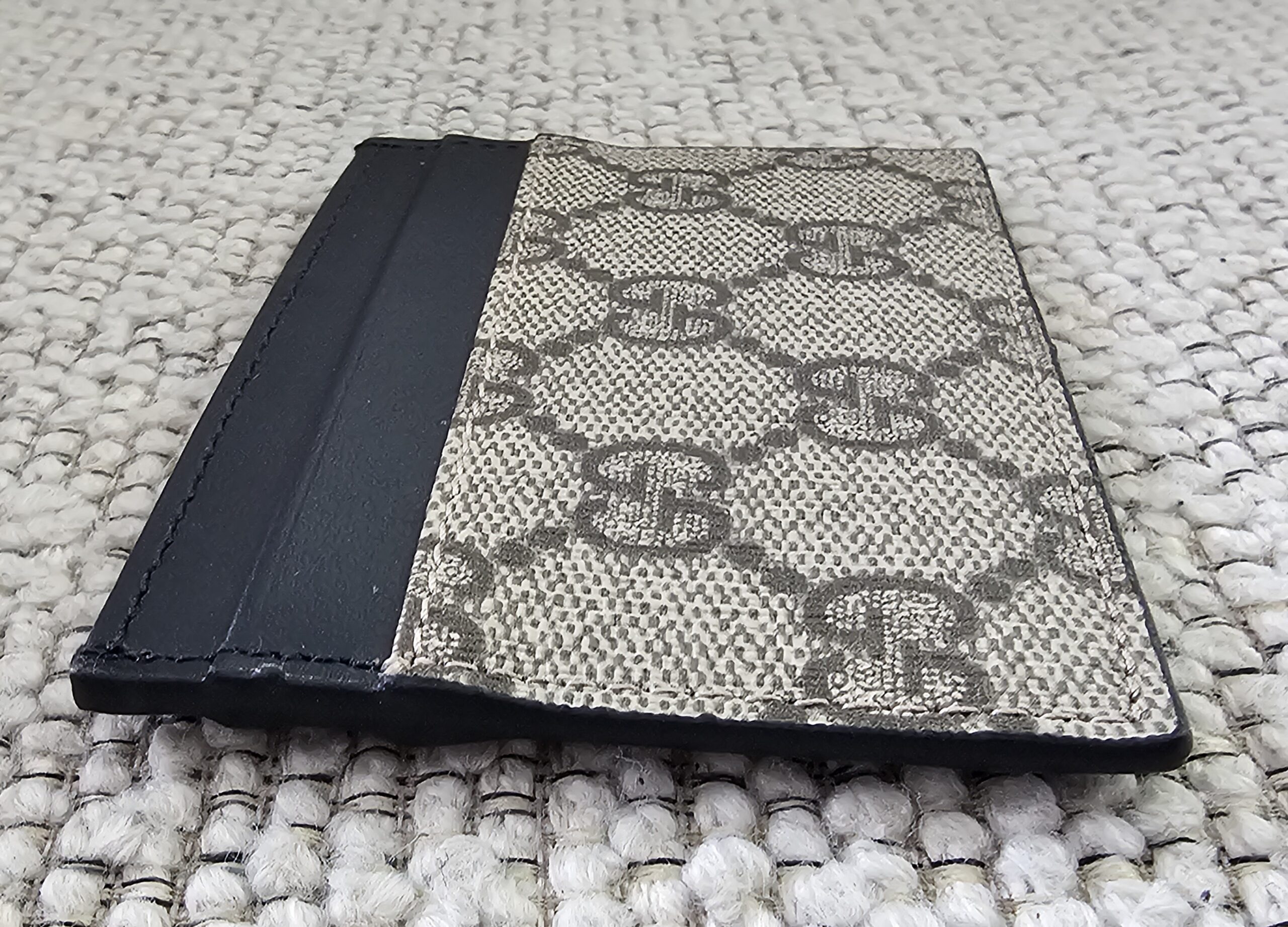 Angled view of the Gucci GG Supreme Essence card holder with black calfskin trim