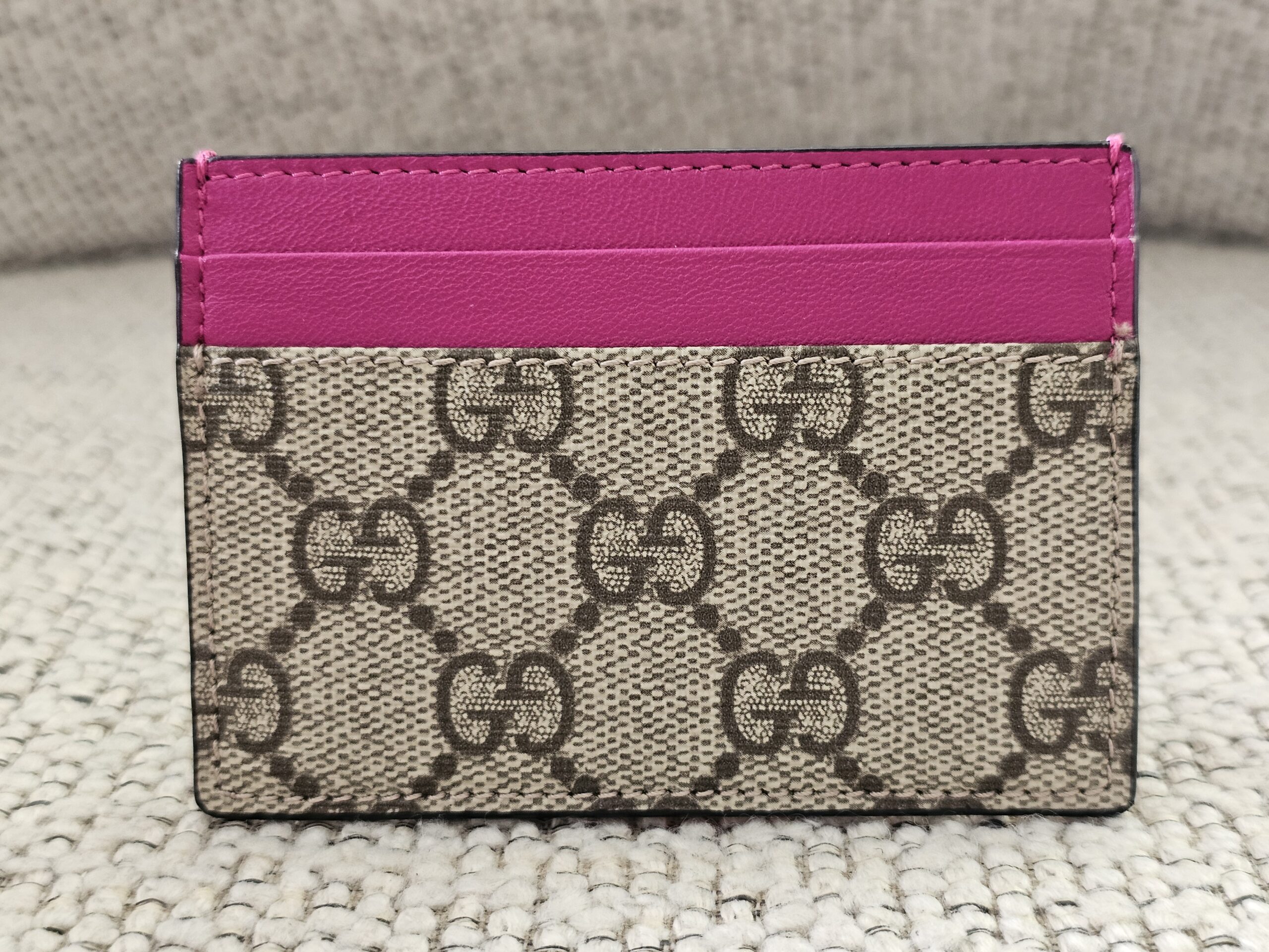 Front of the Gucci Essence card holder showing the GG Supreme canvas and pink calfskin card slots