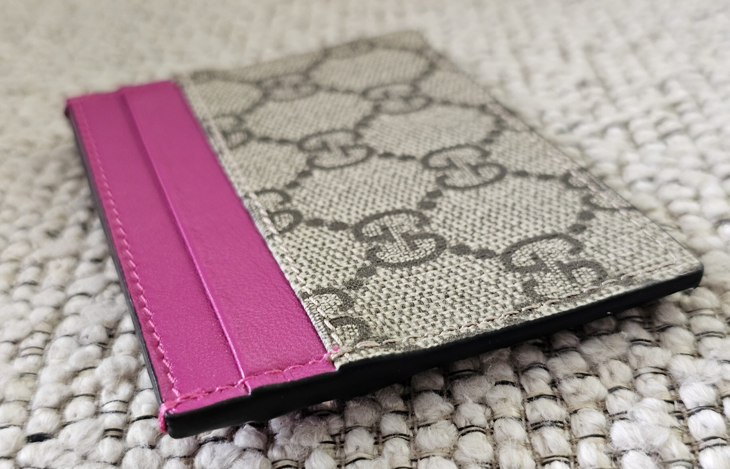 Angled view of the Gucci GG Supreme Essence card holder with pink calfskin trim