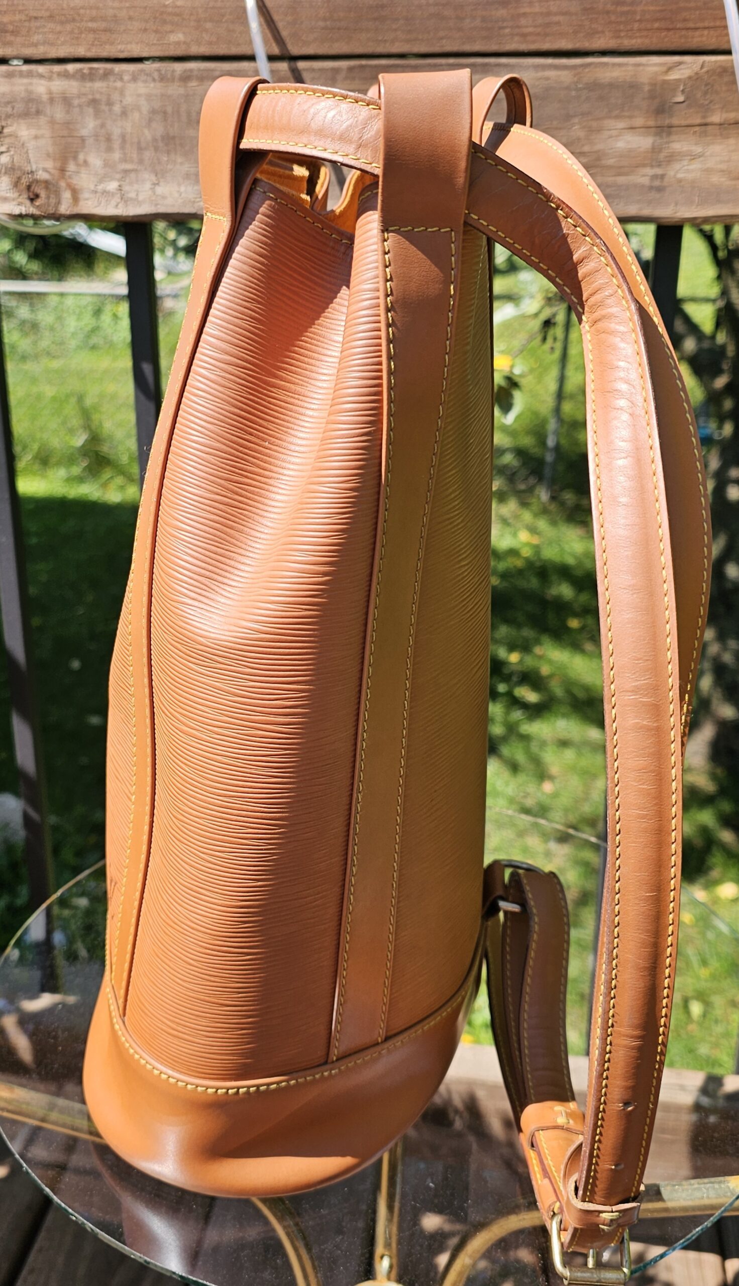 Side profile of the Louis Vuitton Epi Randonnee PM showing the backpack strap