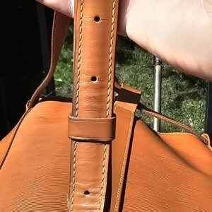Single leather cinch strap of the Louis Vuitton Epi Randonnee PM held in hand