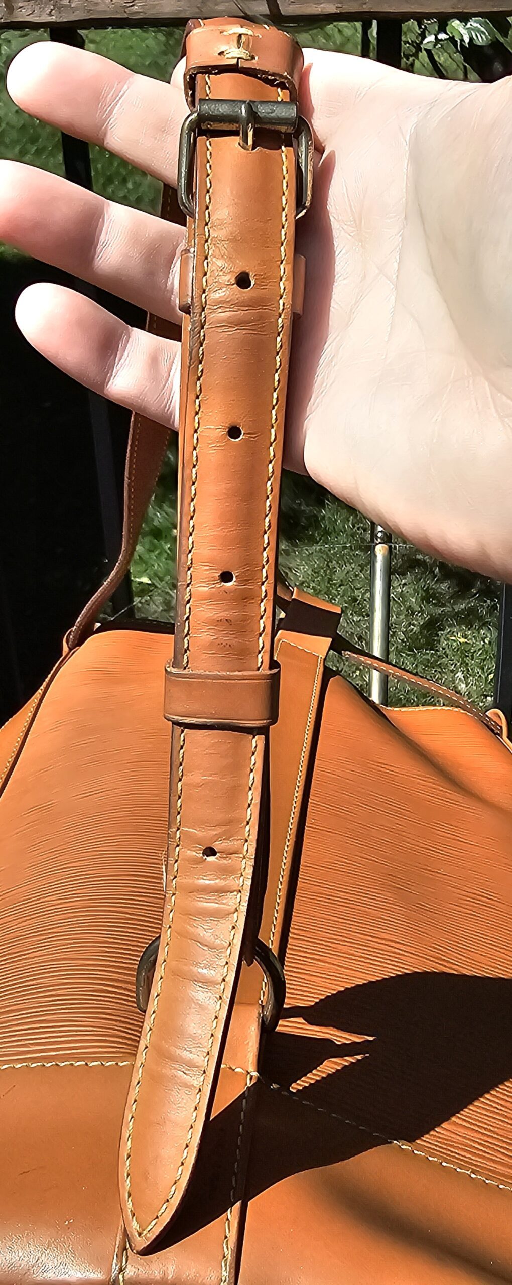 Single leather cinch strap of the Louis Vuitton Epi Randonnee PM held in hand