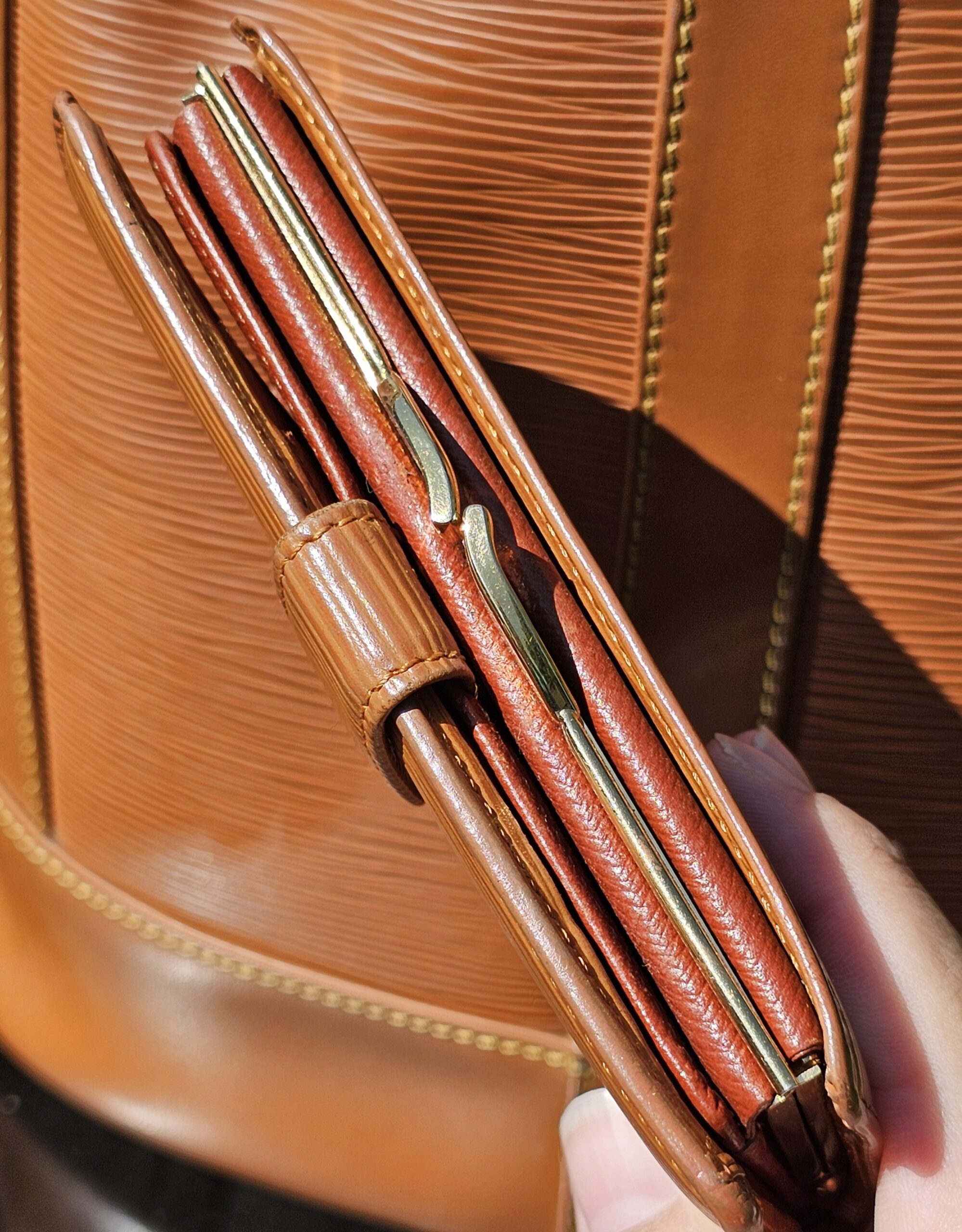 Louis Vuitton Epi kisslock wallet held open showing its compartments