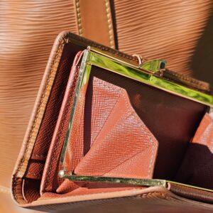 Kisslock clasp hardware on the Louis Vuitton Epi wallet showing tarnish from age