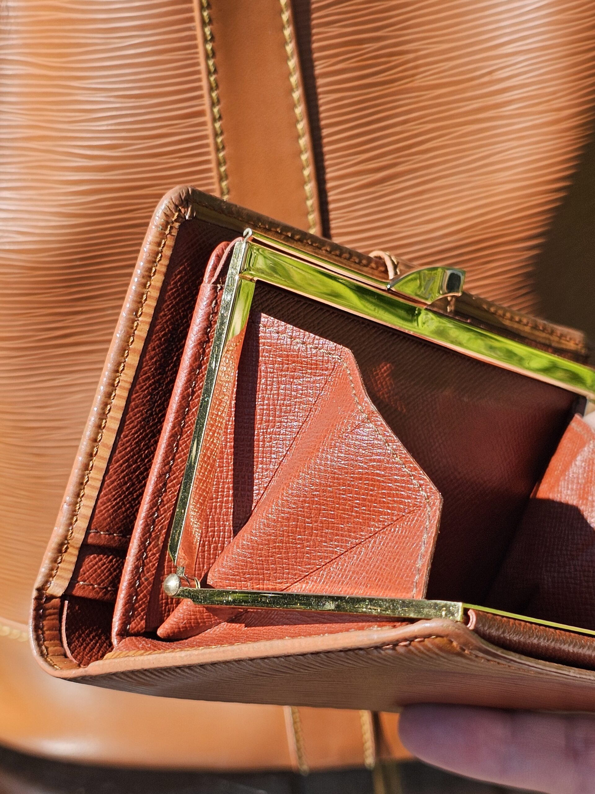 Kisslock clasp hardware on the Louis Vuitton Epi wallet showing tarnish from age