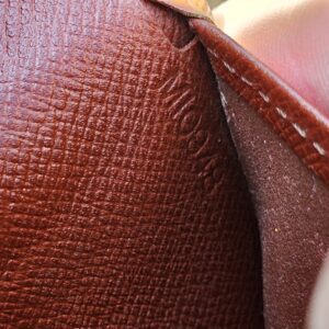 Interior of the Louis Vuitton Epi kisslock wallet shown for coin residue and wear