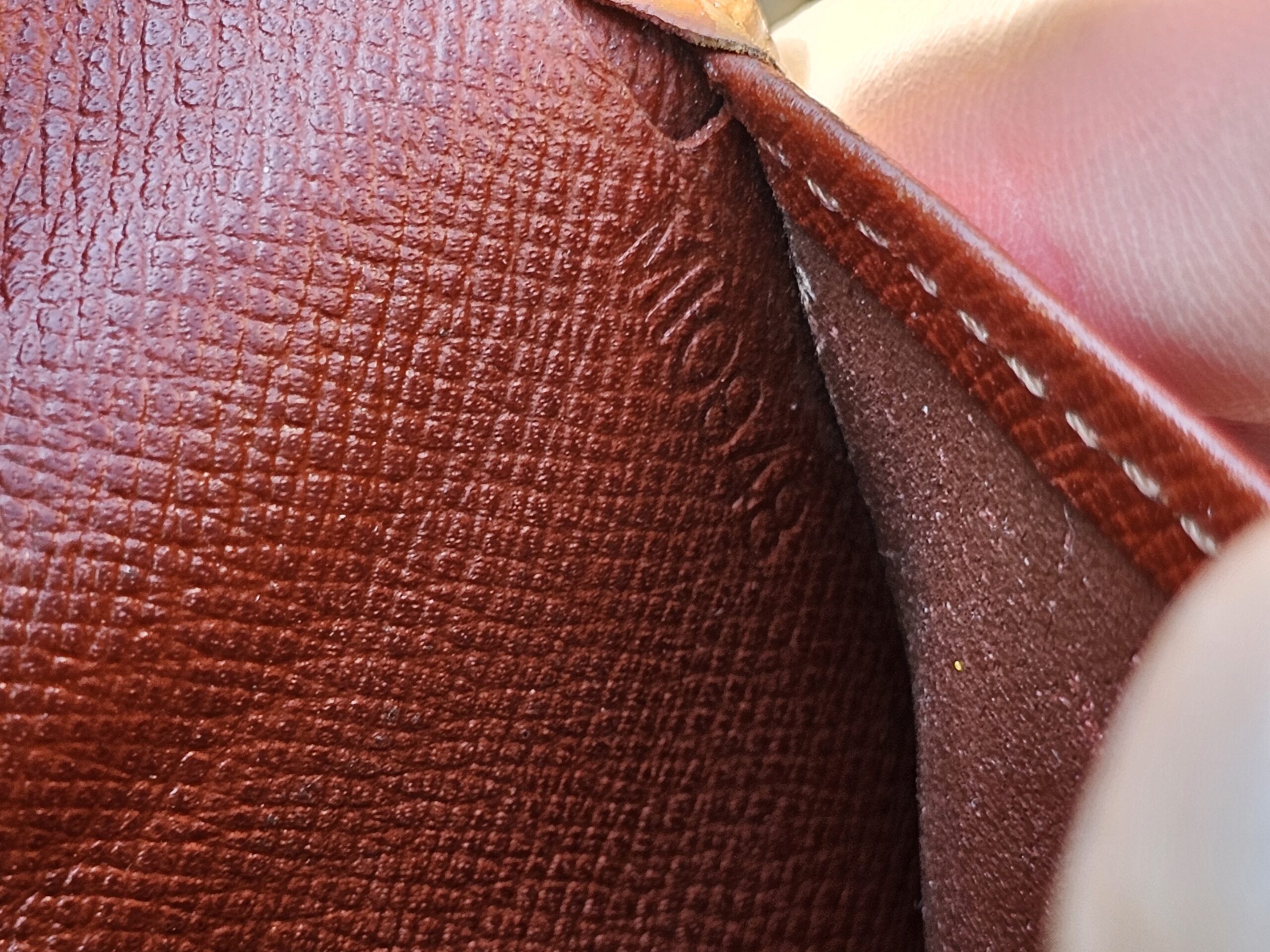 Interior of the Louis Vuitton Epi kisslock wallet shown for coin residue and wear