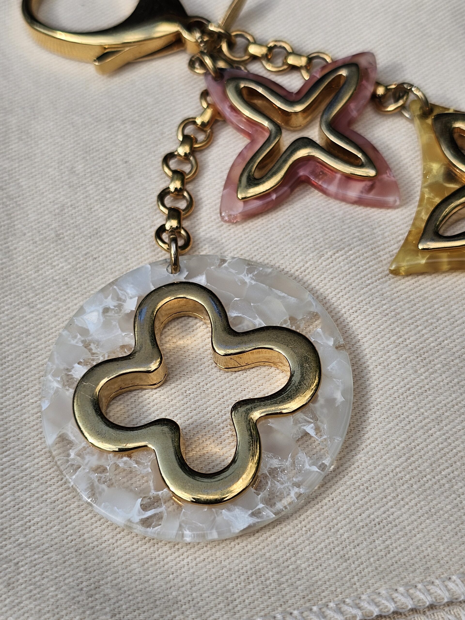 Pearly white resin medallion with a gold-tone Monogram flower on the Louis Vuitton Insolence bag charm