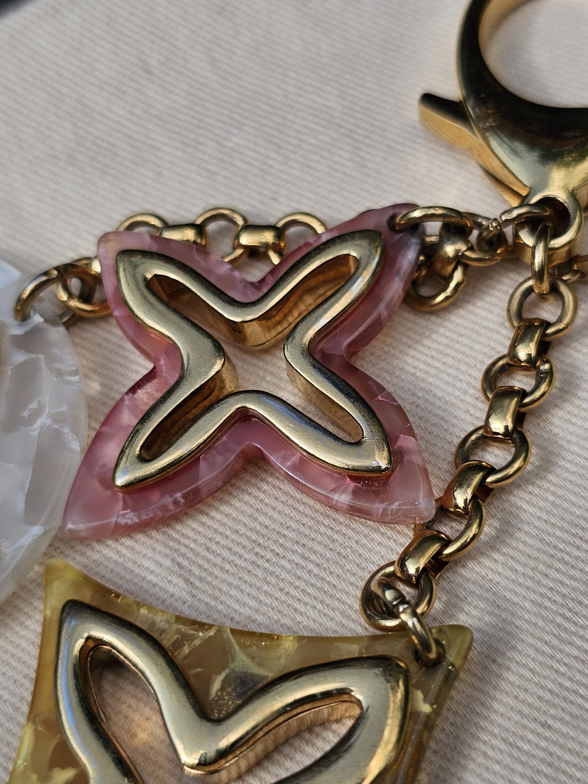 Close-up of the marbled resin and gold-tone Monogram outlines on the Louis Vuitton Insolence charms