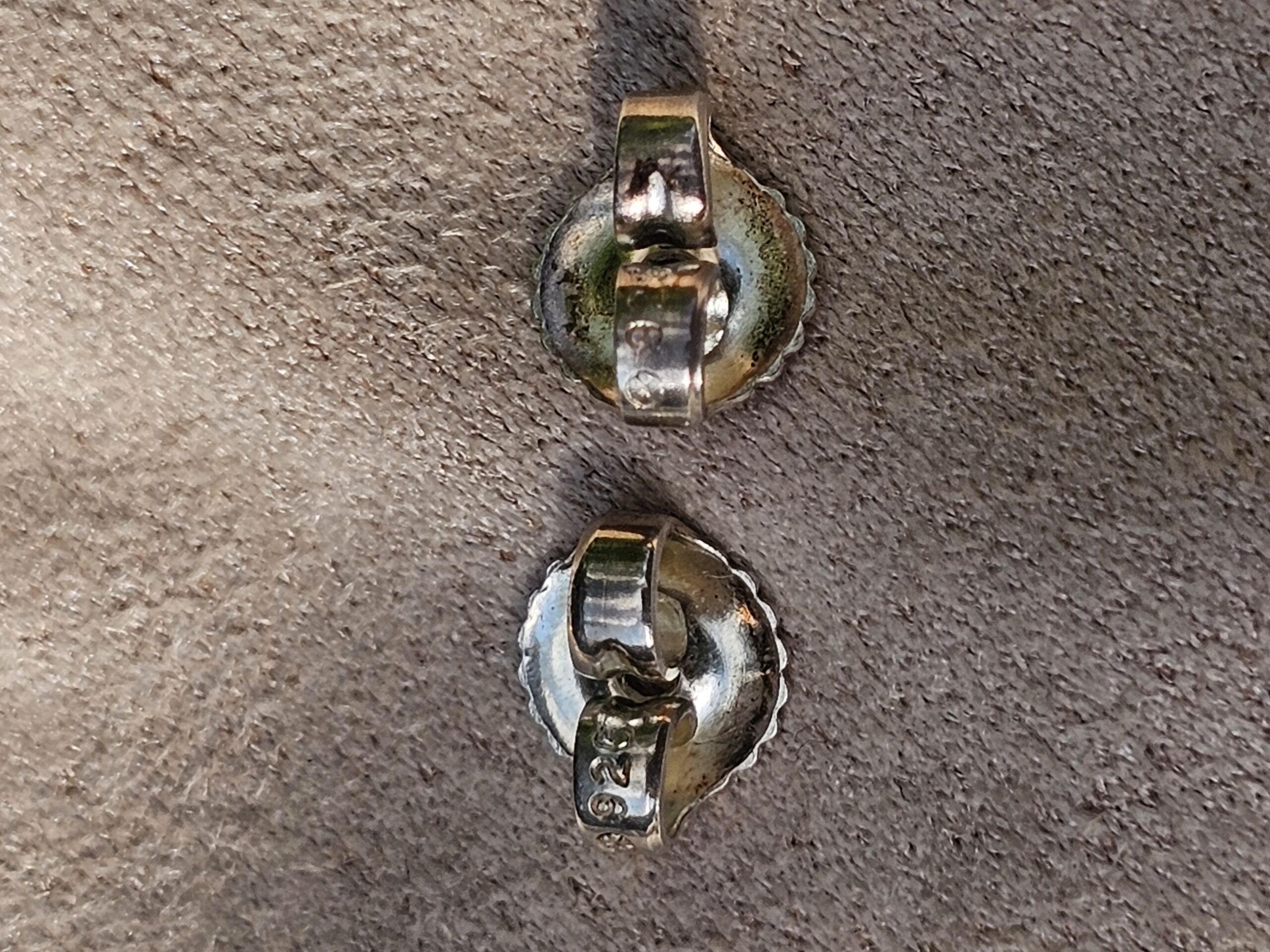 Backs of the Chanel four leaf clover stud earrings shown for wear from previous use