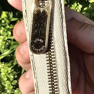 Gold-tone zip pull on the Louis Vuitton Damier Azur Zippy Coin Purse held in hand