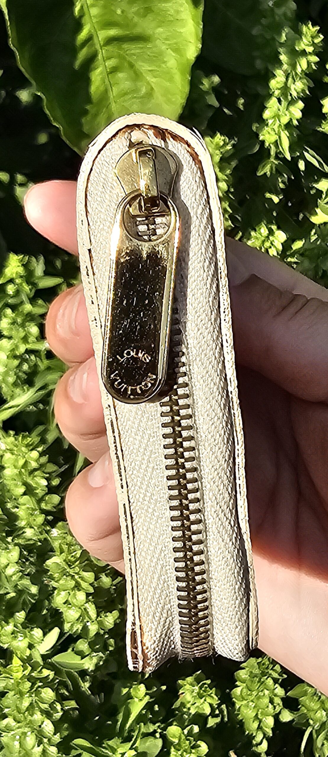 Gold-tone zip pull on the Louis Vuitton Damier Azur Zippy Coin Purse held in hand