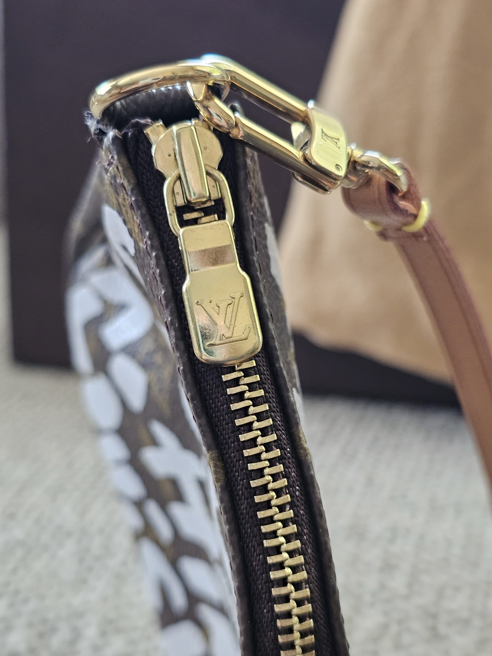 Gold-tone LV zip pull and vachetta strap on the Stephen Sprouse Graffiti Pochette Accessoires